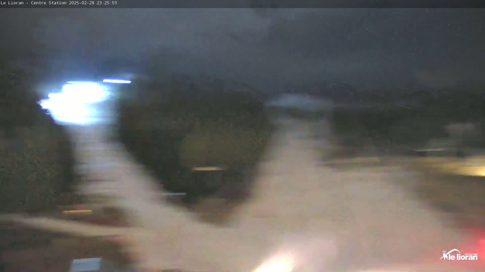 A blurry, nighttime image shows bright lights streaking across a dark, possibly snowy or foggy scene.