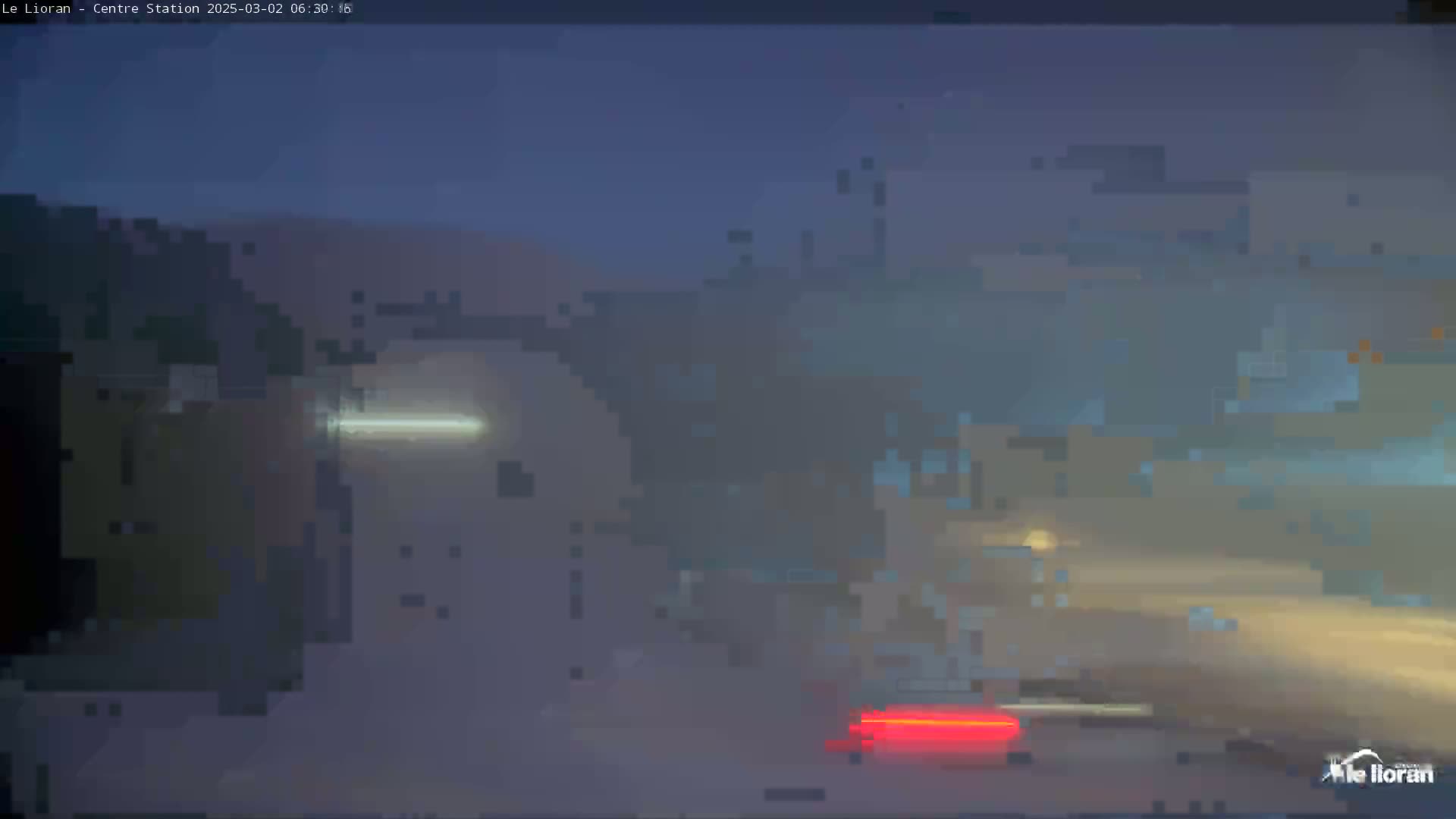 A hazy, dimly lit outdoor scene shows blurry images of vehicles and buildings at night.