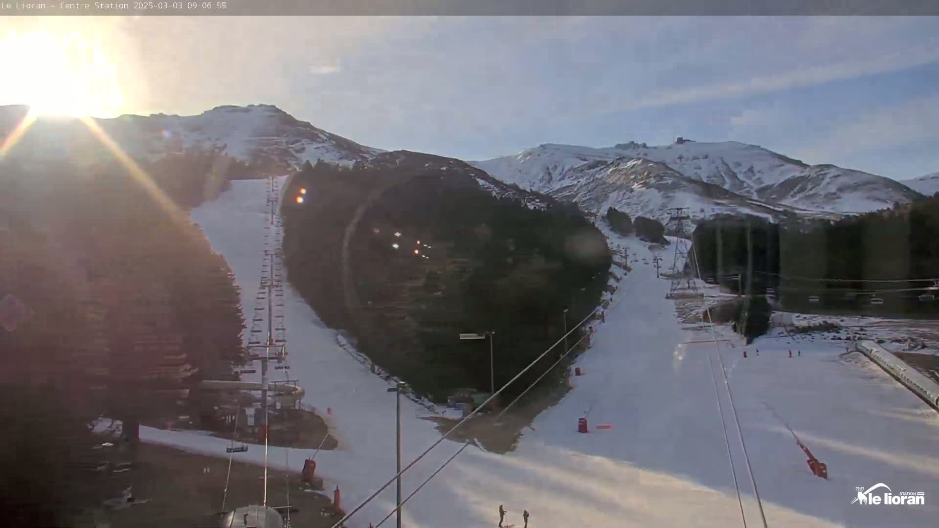 A sunny, snow-covered ski resort with ski lifts and several runs visible on a mountainside.
