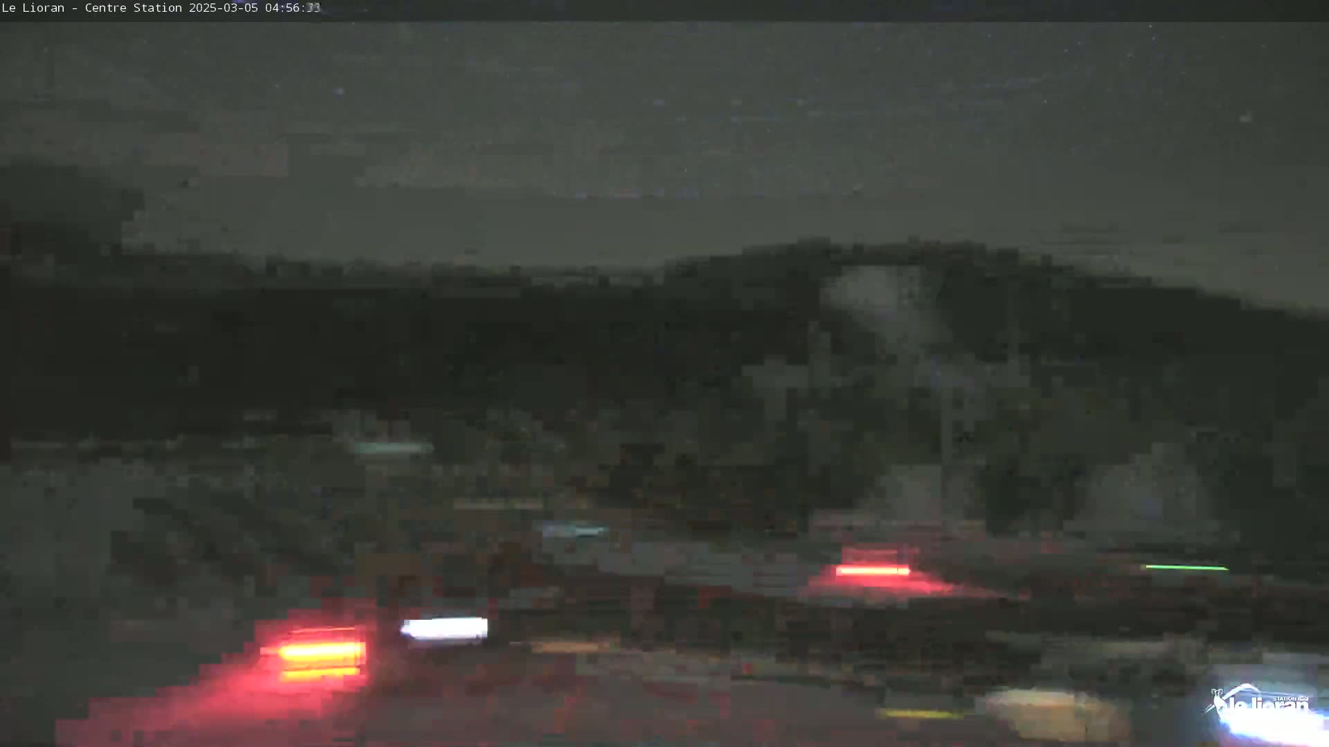 A nighttime, blurry view of a road with several vehicles' taillights visible under a dark, possibly starry sky.