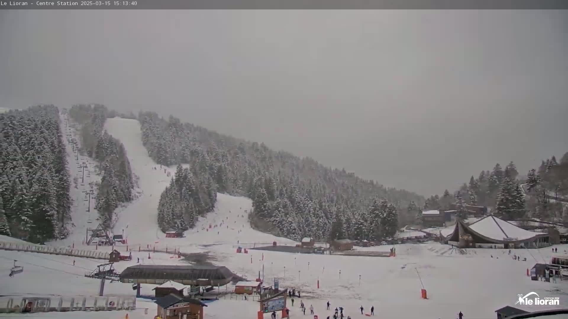 A snow-covered ski resort with several ski slopes and lift systems is visible under an overcast sky.