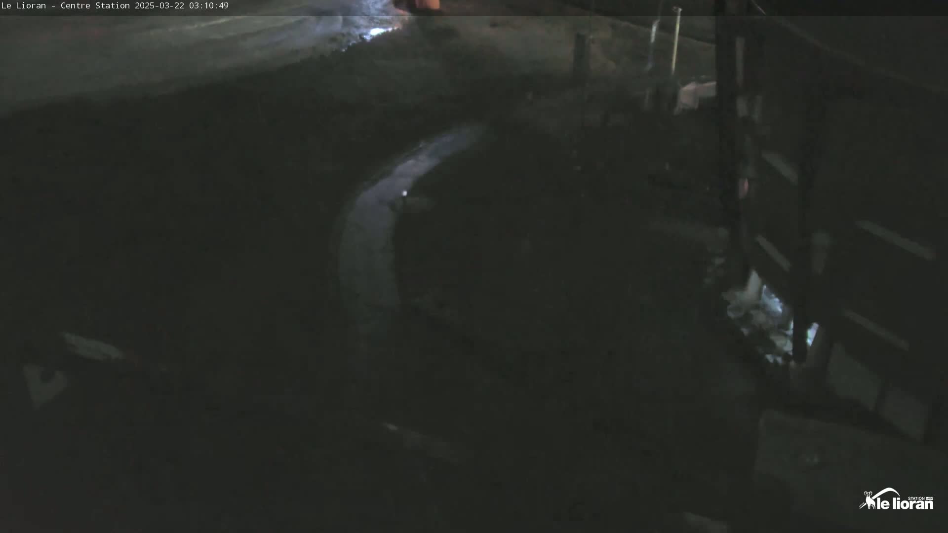 A nighttime, overhead view shows a dimly lit, curving pathway next to a dark building.
