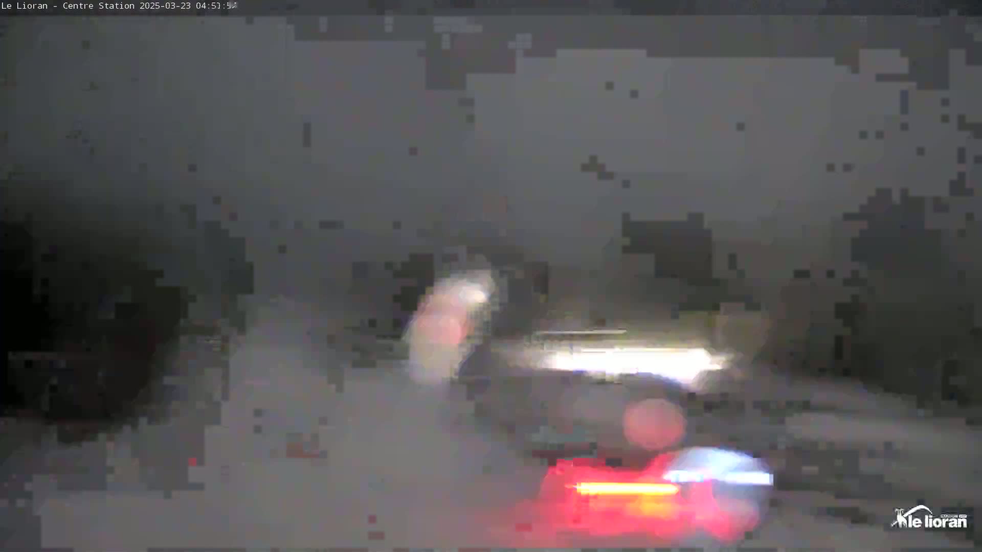 A blurry image shows a dark, snowy night scene with the rear lights of a vehicle visible in the foreground.
