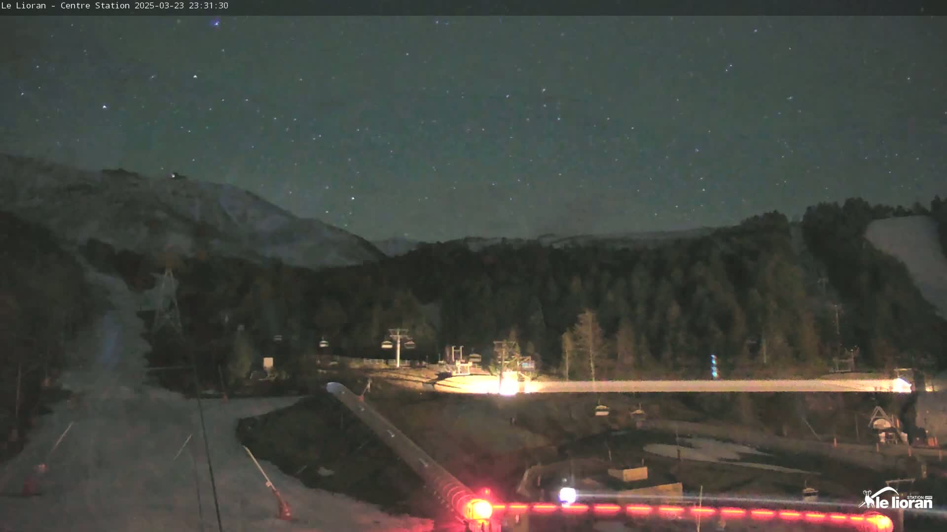 A nighttime view of a snow-covered ski resort under a clear, starry sky.