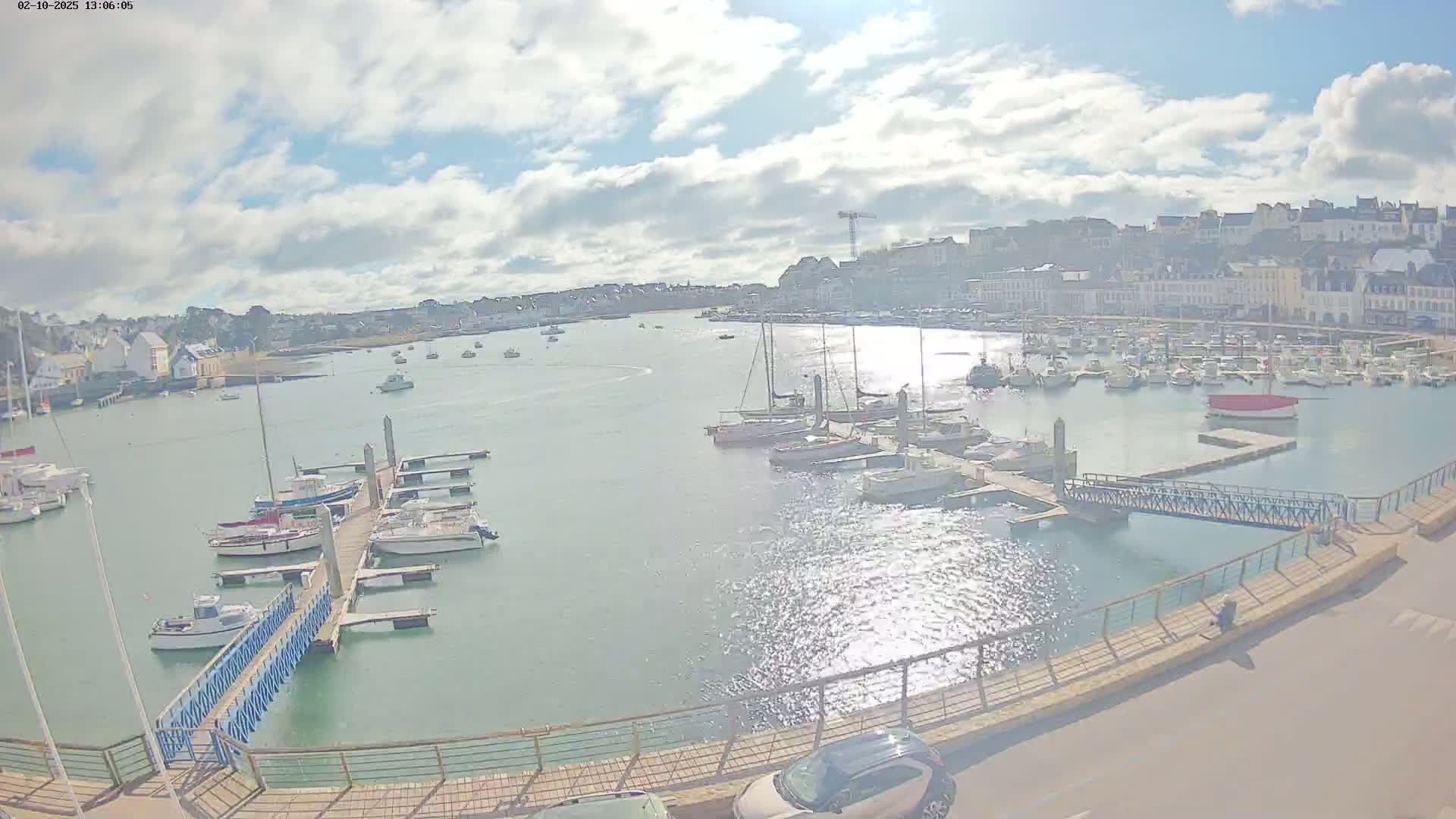 A harbor filled with sailboats and motorboats under a partly sunny sky.