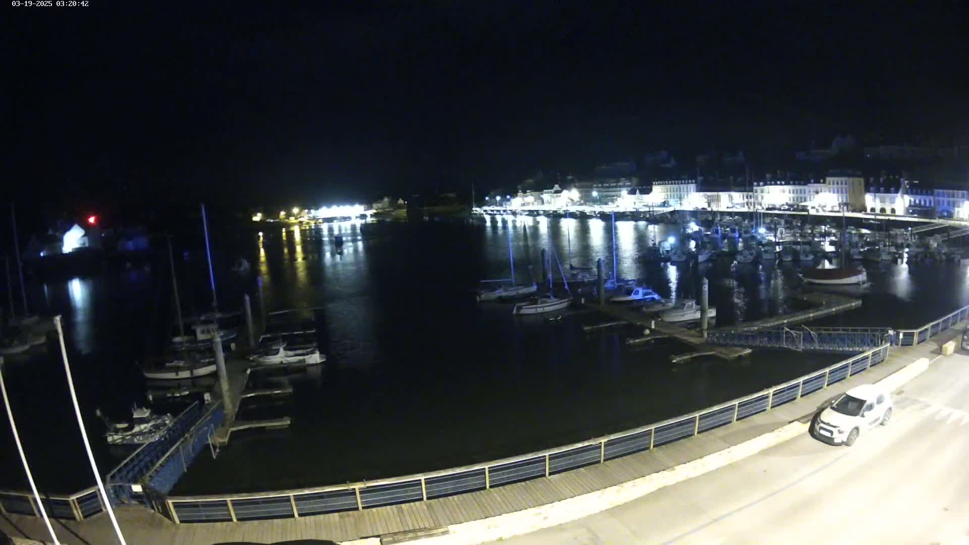 A nighttime view of a harbor filled with boats, docked along a lit waterfront.