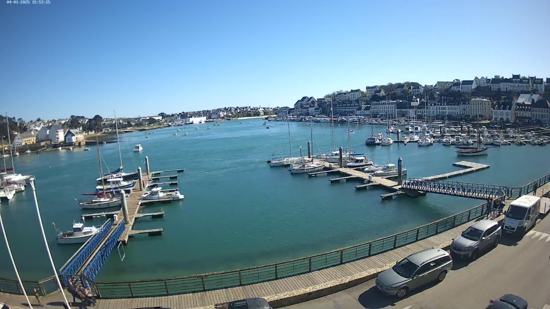 A harbor filled with boats on a sunny day, overlooked by a town of white buildings.