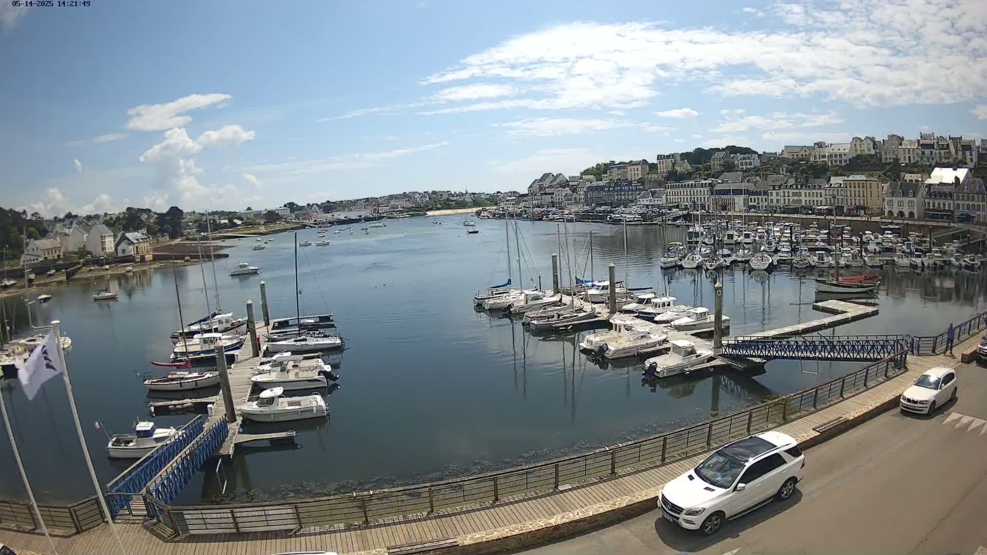 A harbor filled with numerous sailboats and motorboats under a mostly sunny sky.