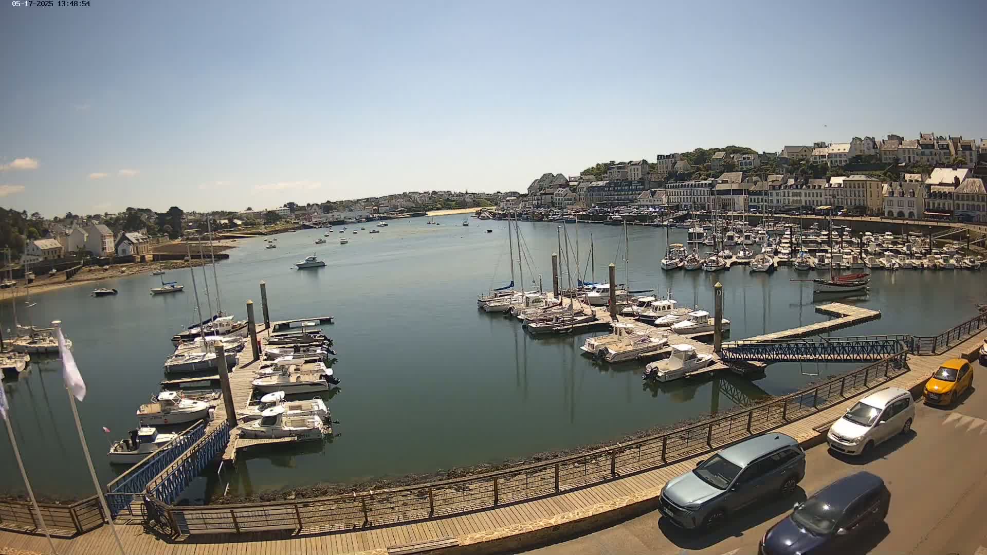 A harbor filled with many boats on a sunny day, with a town and buildings visible in the background.