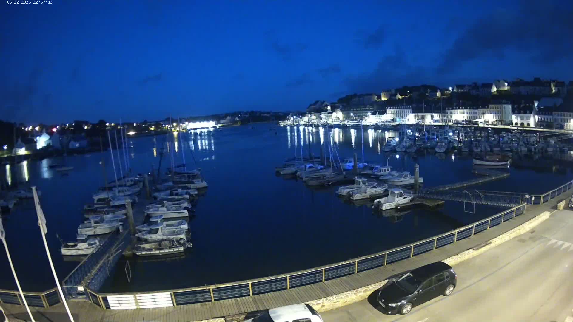 A harbor filled with numerous boats at night under a dark blue, mostly clear sky.
