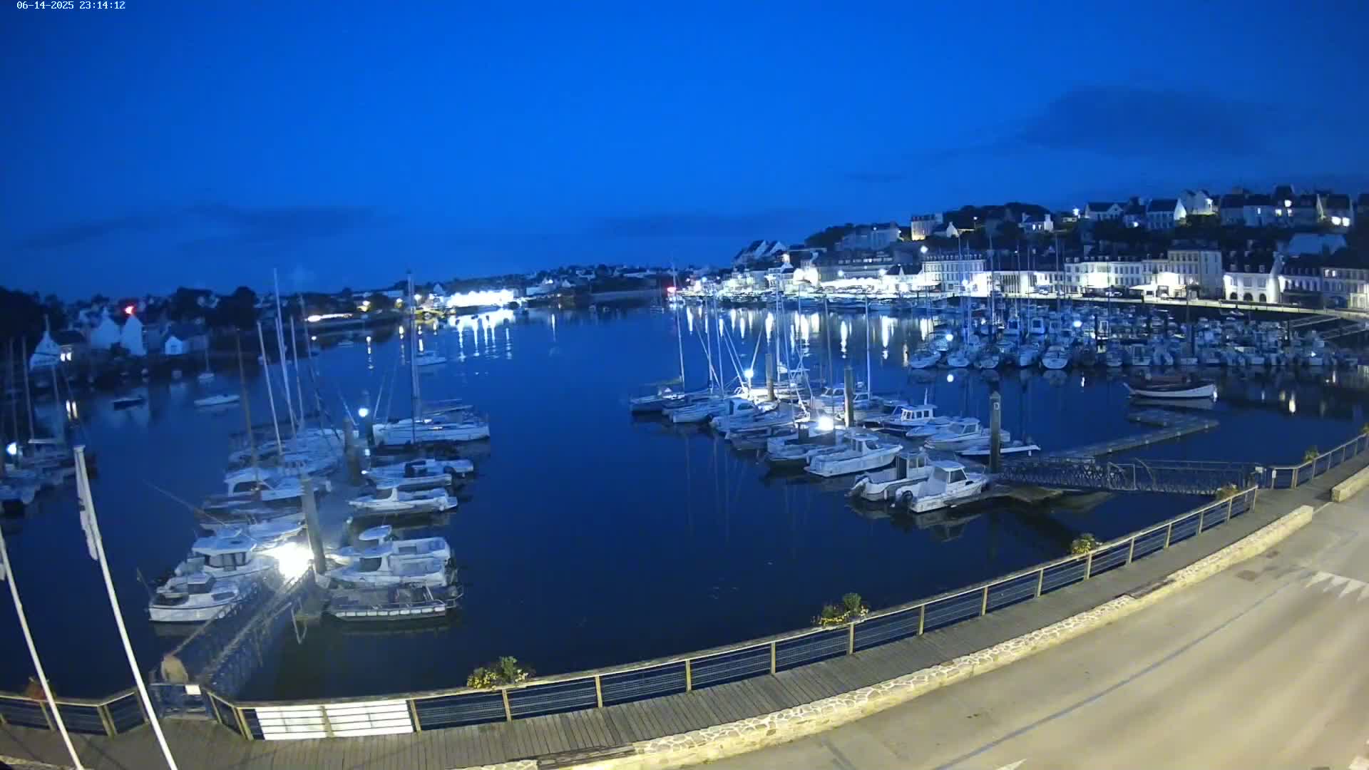 A harbor filled with numerous boats and yachts is nestled beside a town under a clear, sunny sky.
