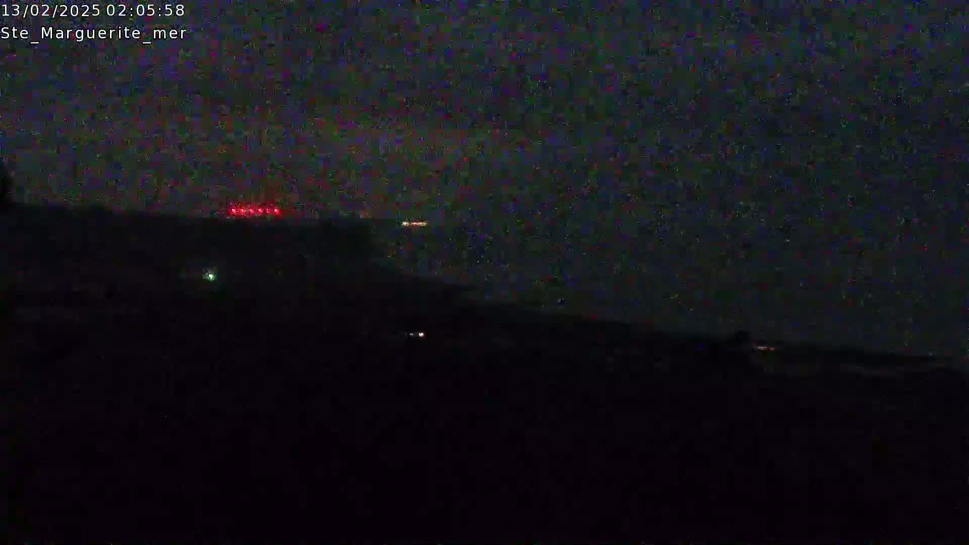 A nighttime, dark landscape is visible with a few faint lights in the distance.
