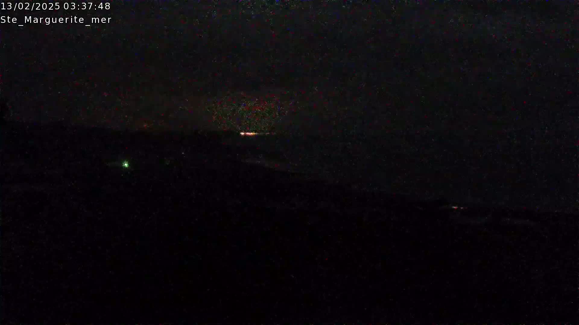 A dark, nighttime scene shows a faint, reddish glow on the horizon under an overcast sky.