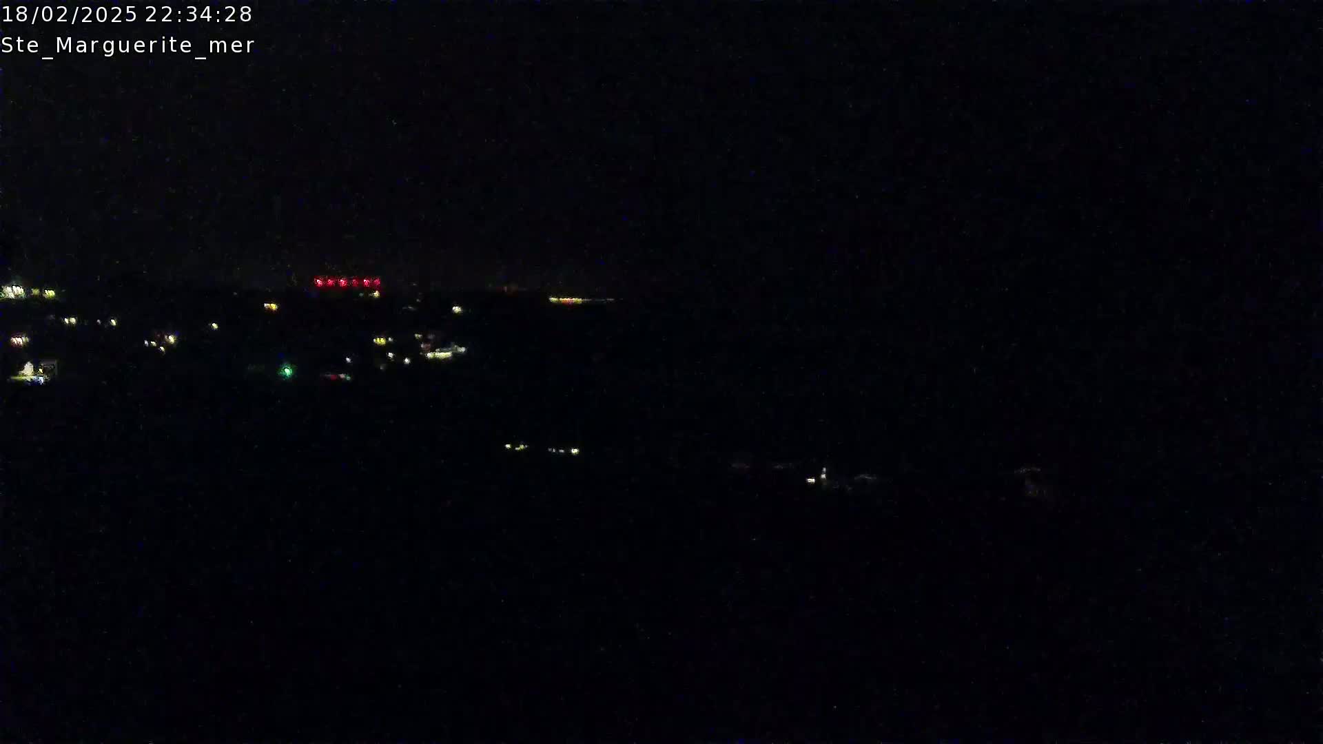 A nighttime, dark scene shows a distant line of lights across a black landscape.