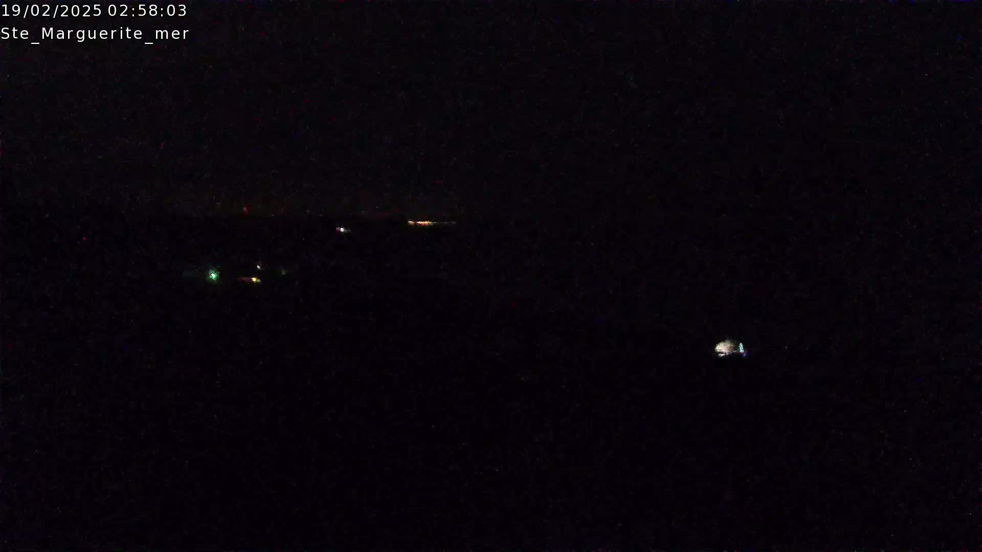 A nighttime, dark image shows a few distant lights on the horizon.