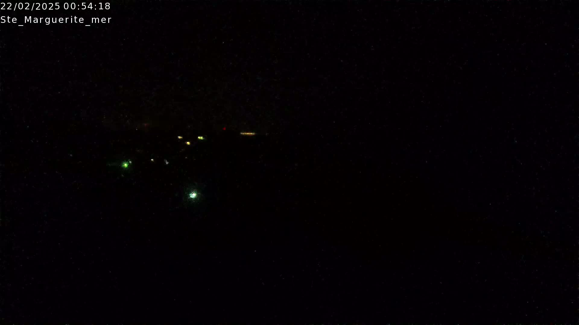 A nighttime, low-light view shows a few distant lights in the darkness.