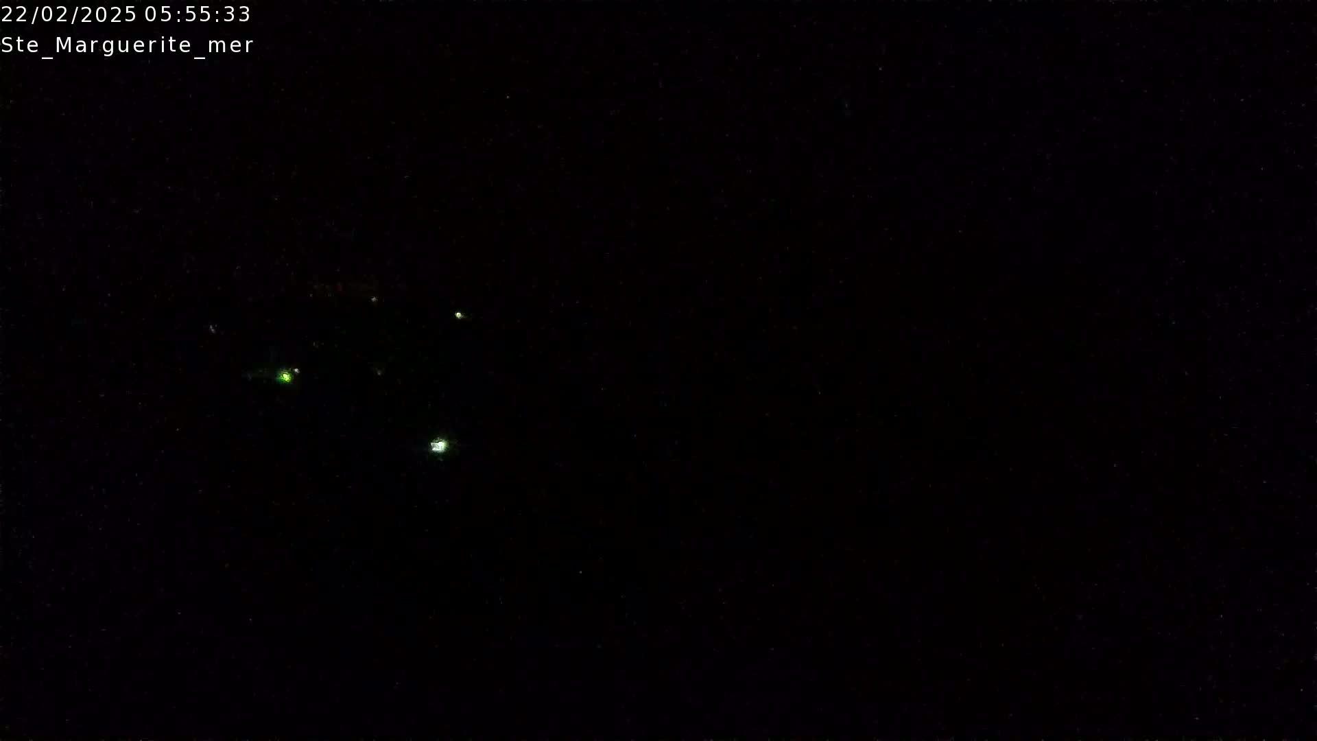 A nighttime, dark image shows a few small, faint lights in the distance.