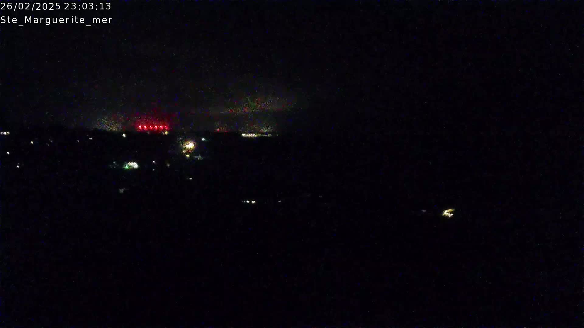 A nighttime long shot shows a dark landscape with sparsely scattered lights and a faint, red glow on the horizon.
