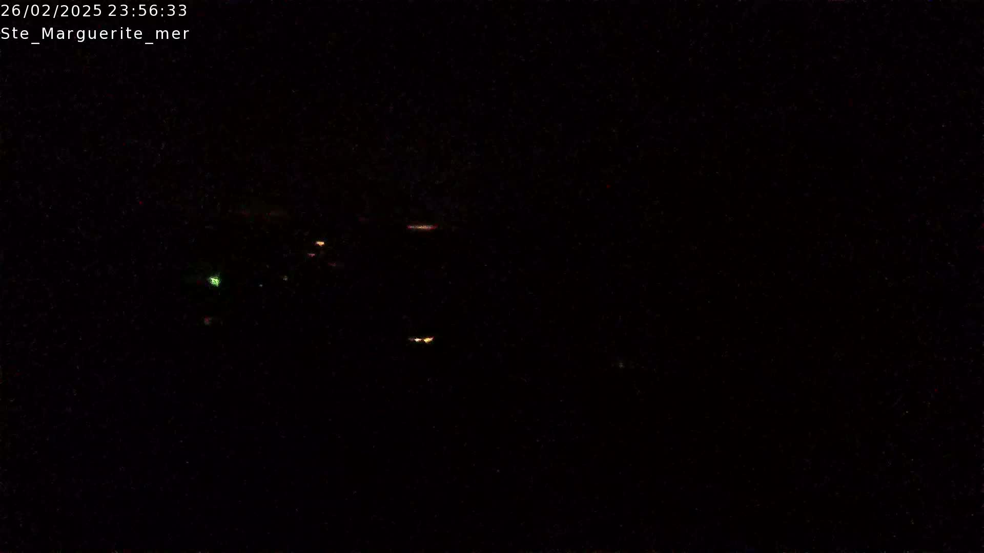 A dark, nighttime scene shows a few faint lights in the distance.