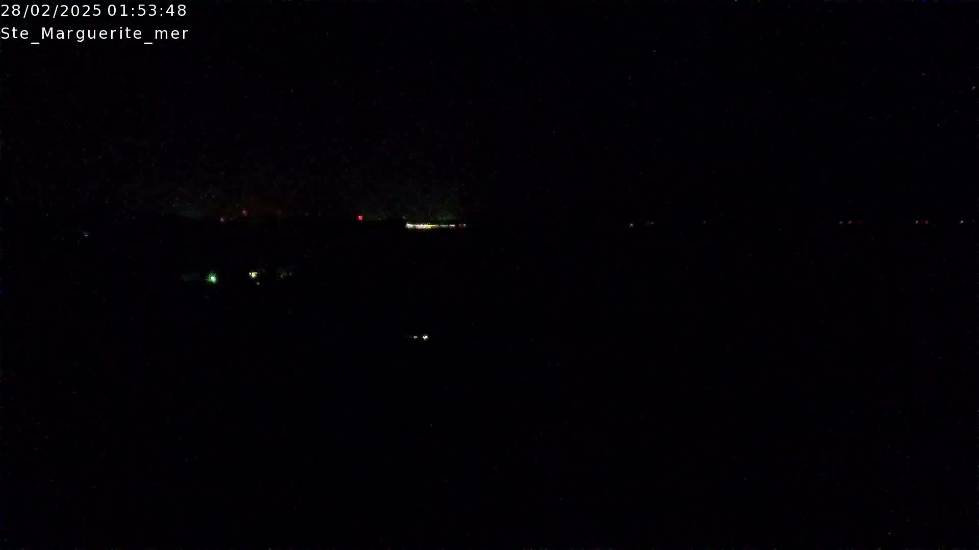 A nighttime, dark landscape is visible with a few distant, faint lights.