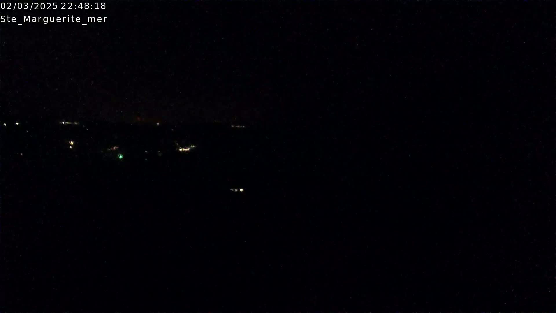 A nighttime, long-range view shows a few distant, faint lights in the dark.