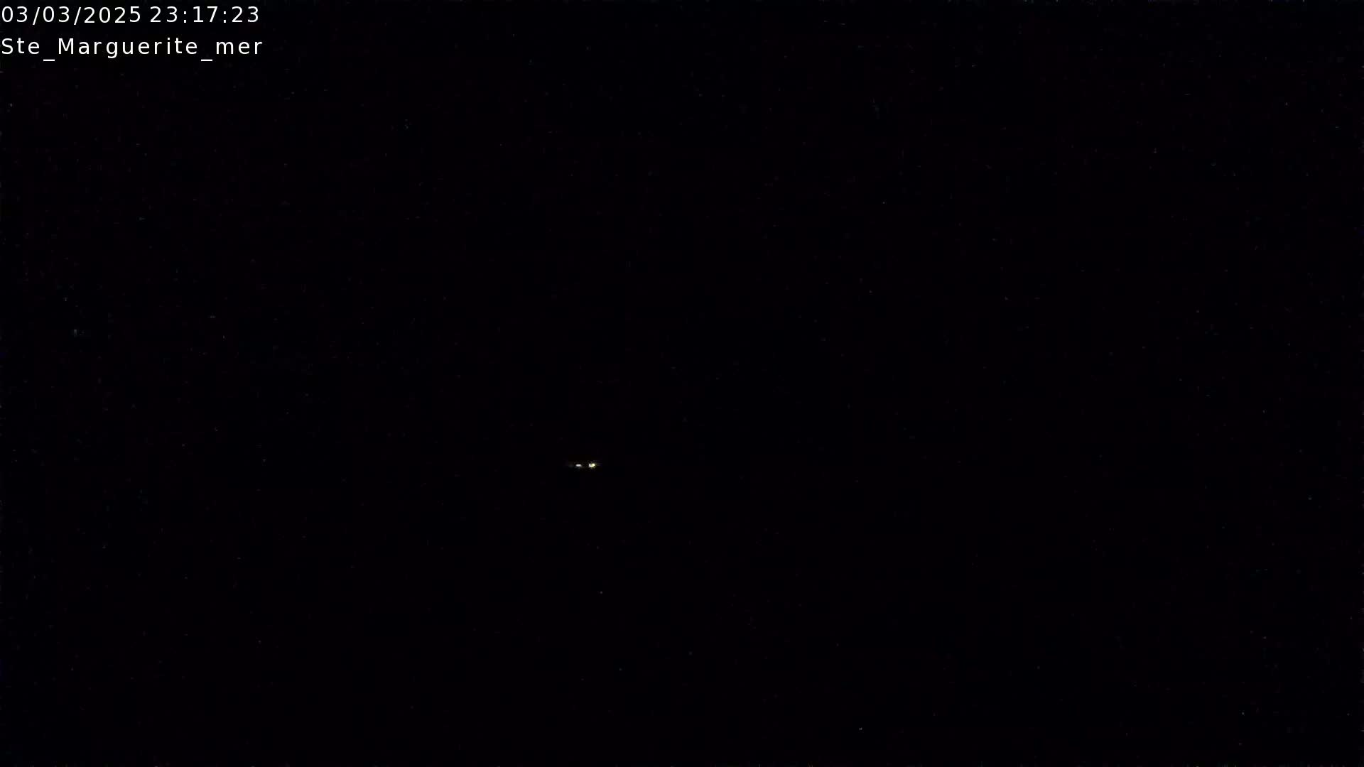 A nighttime image shows two small, faint lights in the distance against a completely dark background.