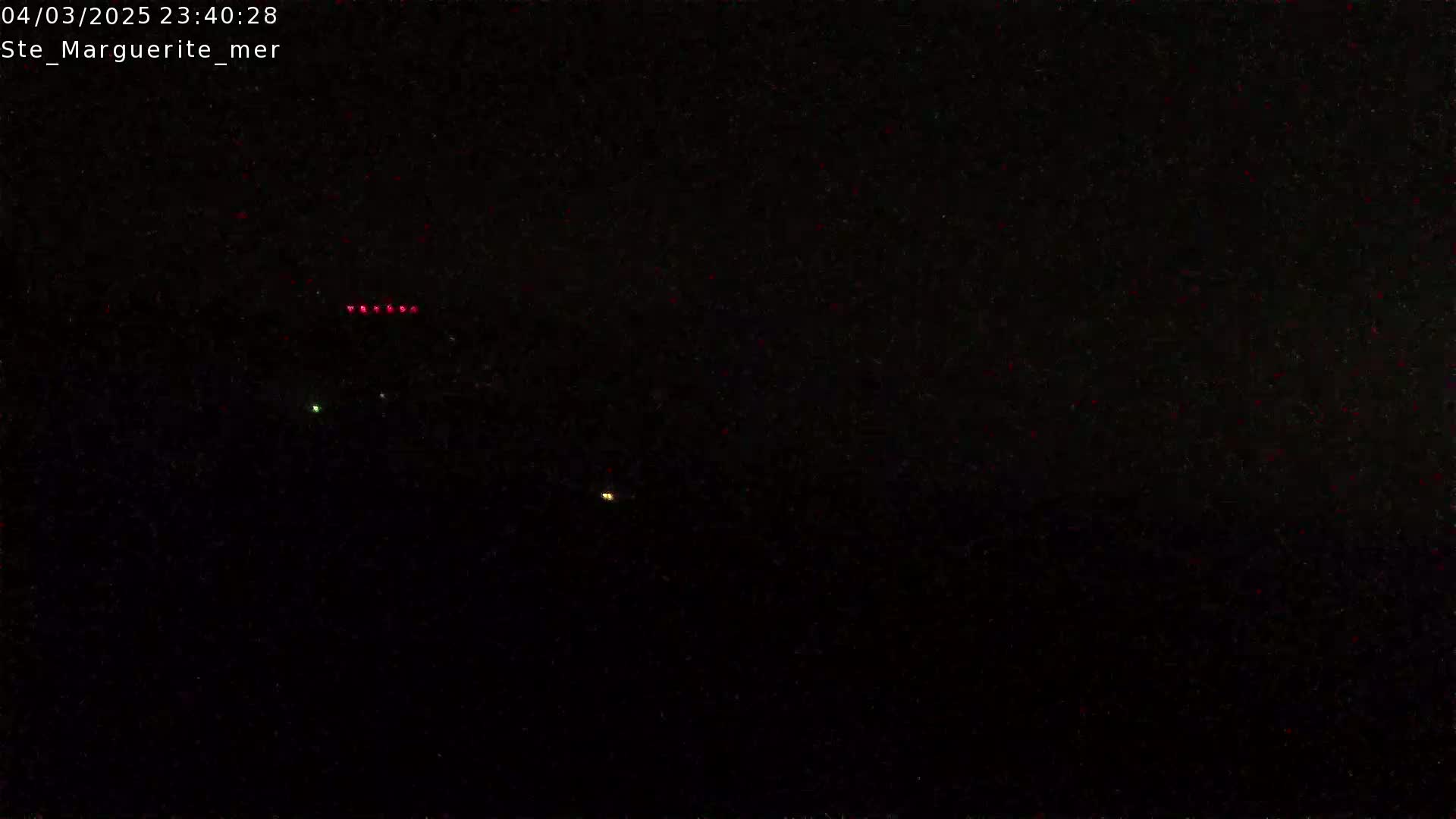 A nighttime, dark scene shows a few small, distant lights.