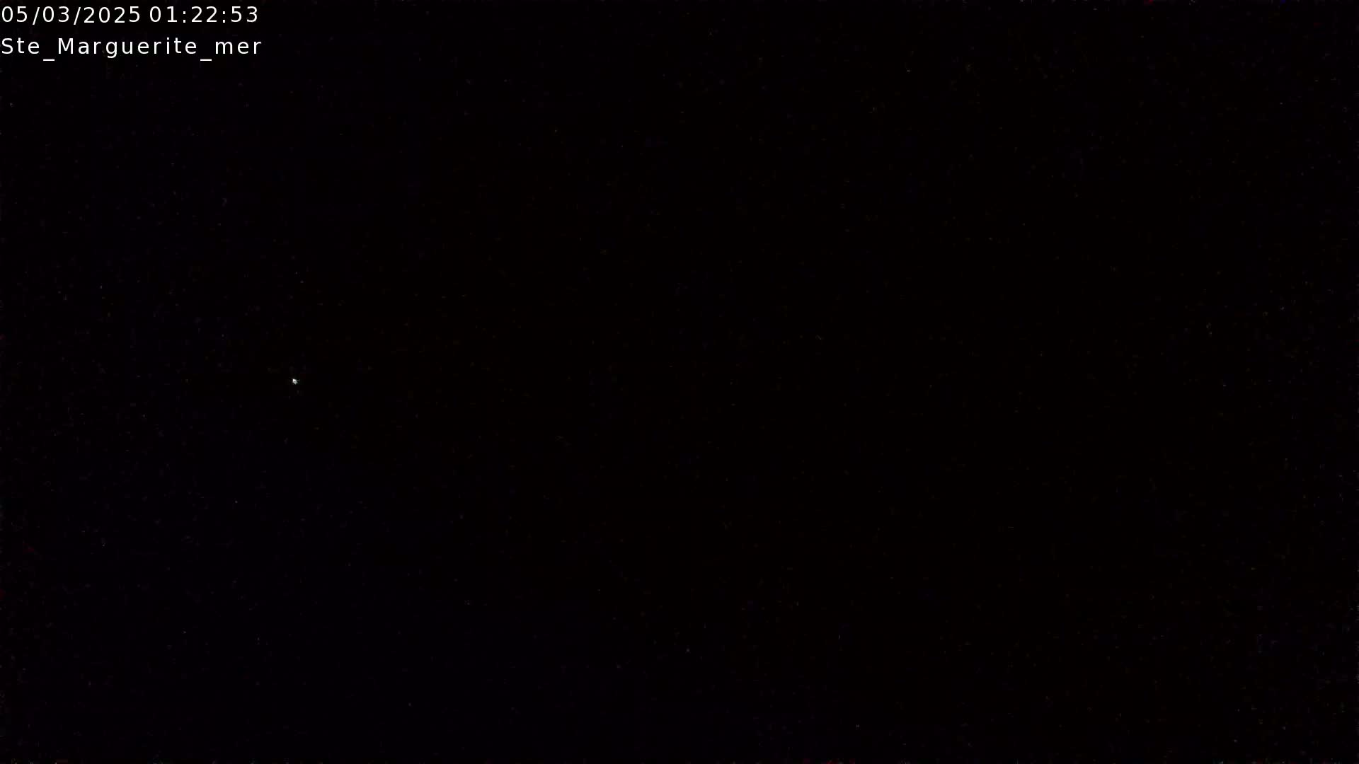 A single, faint light is visible in a mostly dark, nighttime sky.