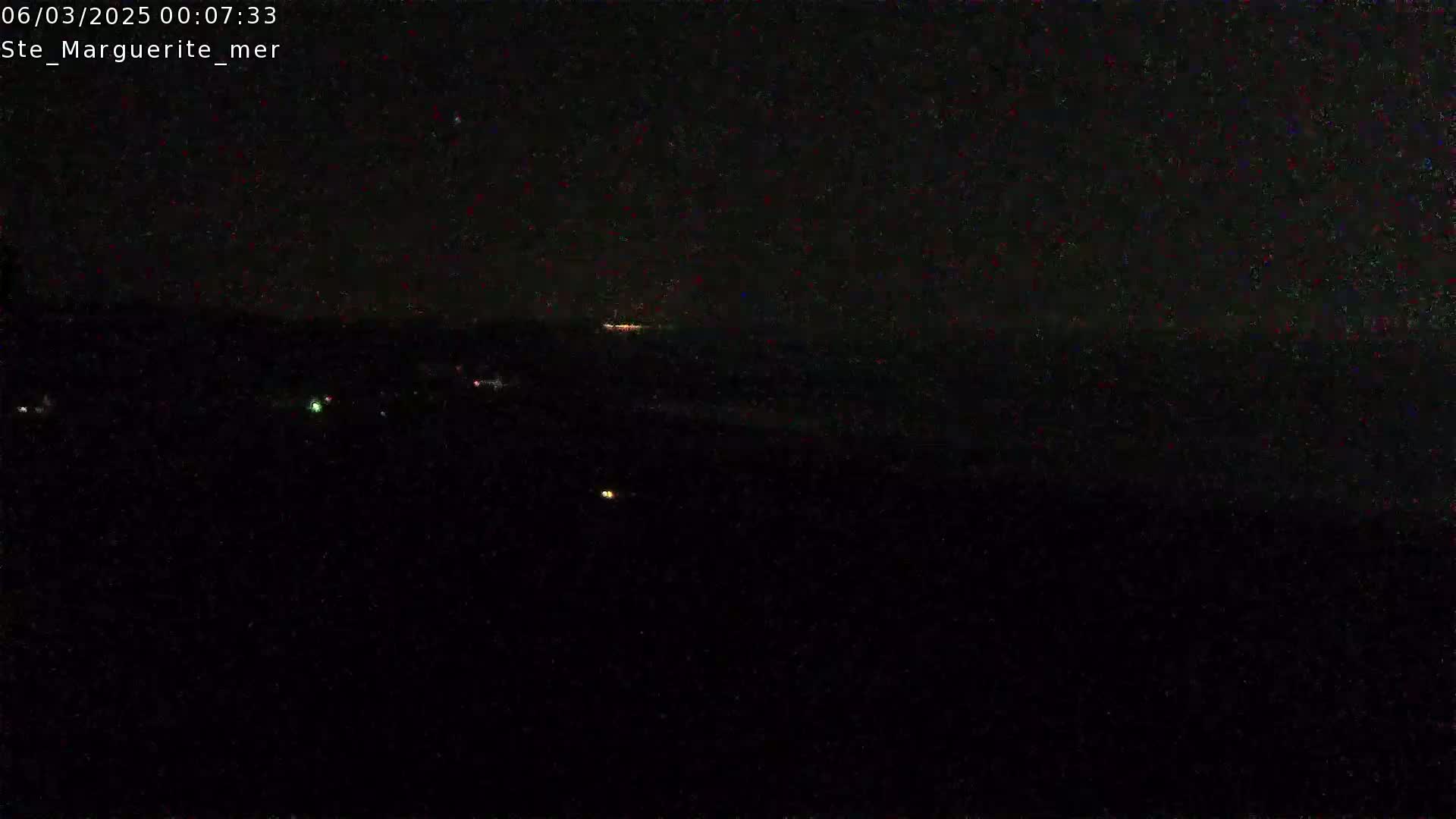 A nighttime, dark view of a body of water with a few faint lights visible in the distance.