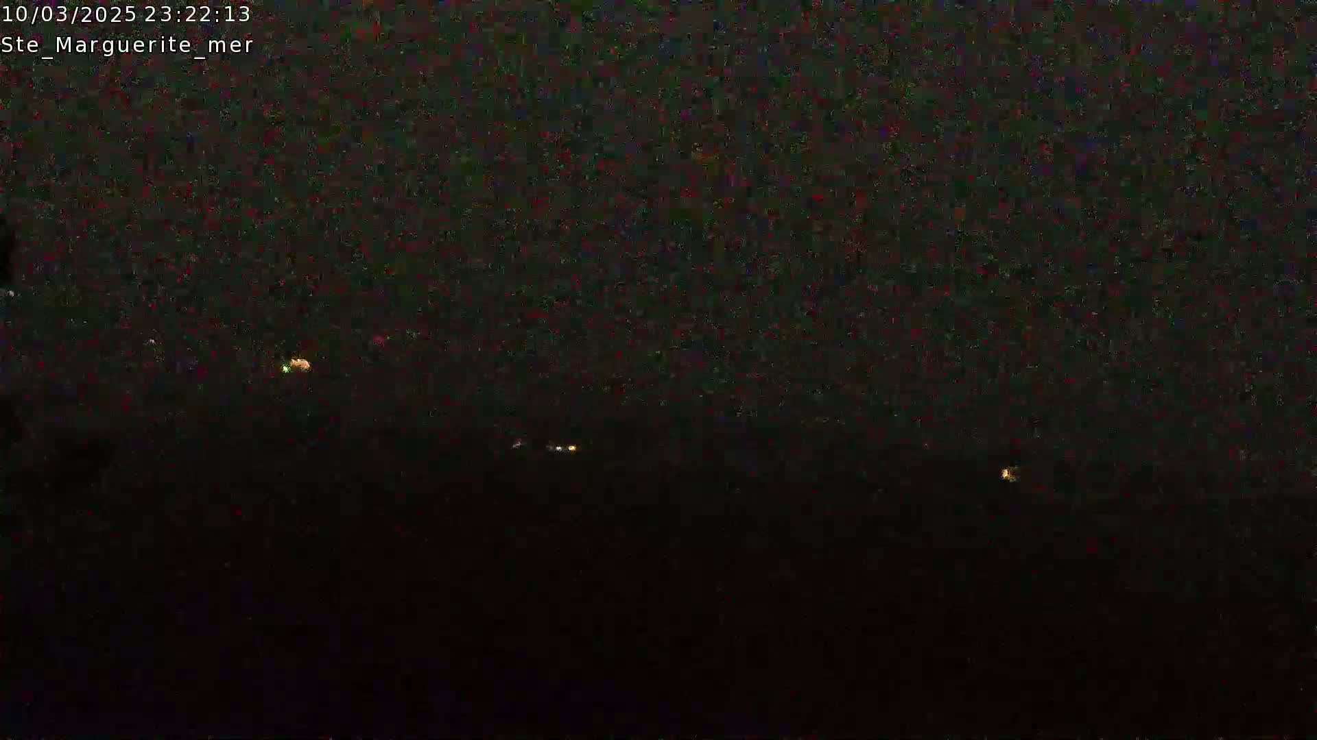 A nighttime, low-light image shows a dark, possibly overcast sky with a few distant, faint lights visible.