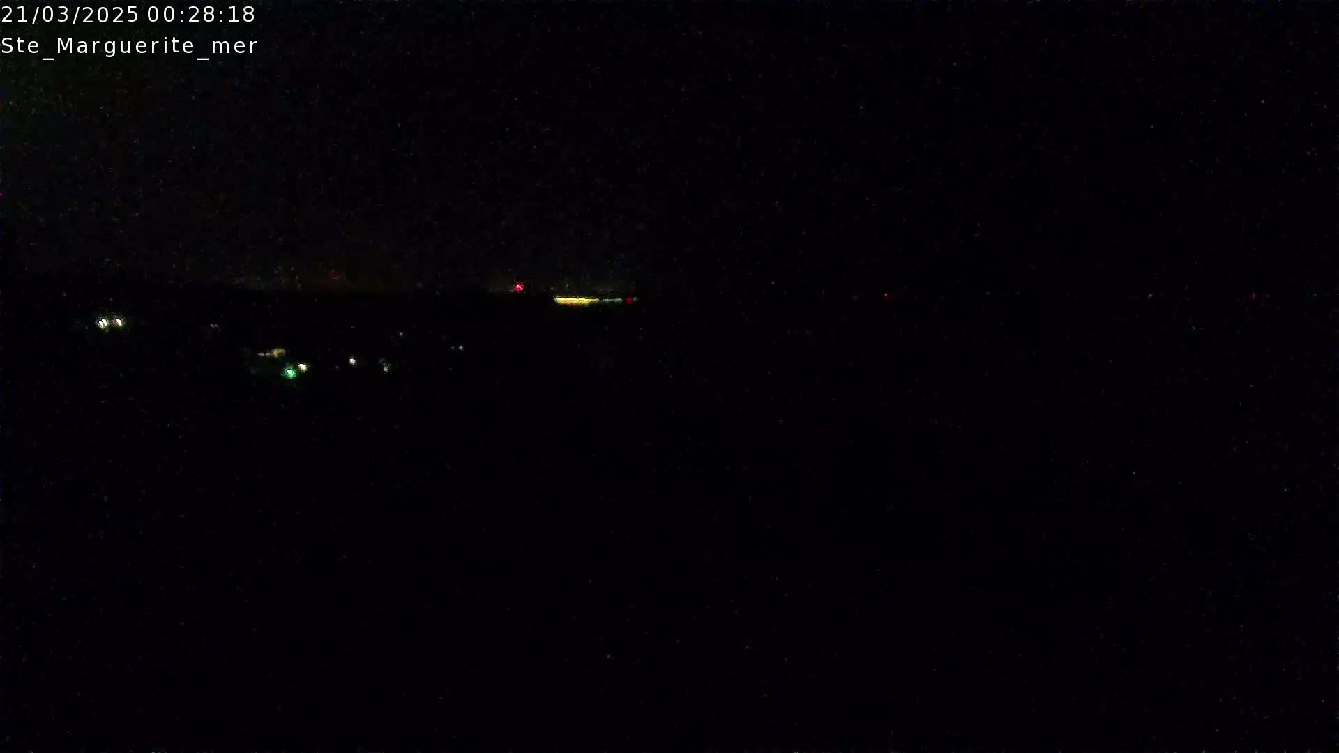 A nighttime, dark view shows a few scattered lights in the distance under a clear, black sky.