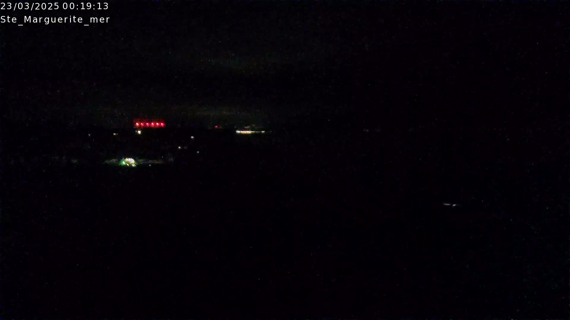 A nighttime long shot shows a dark landscape with a few distant lights, under a dark sky.