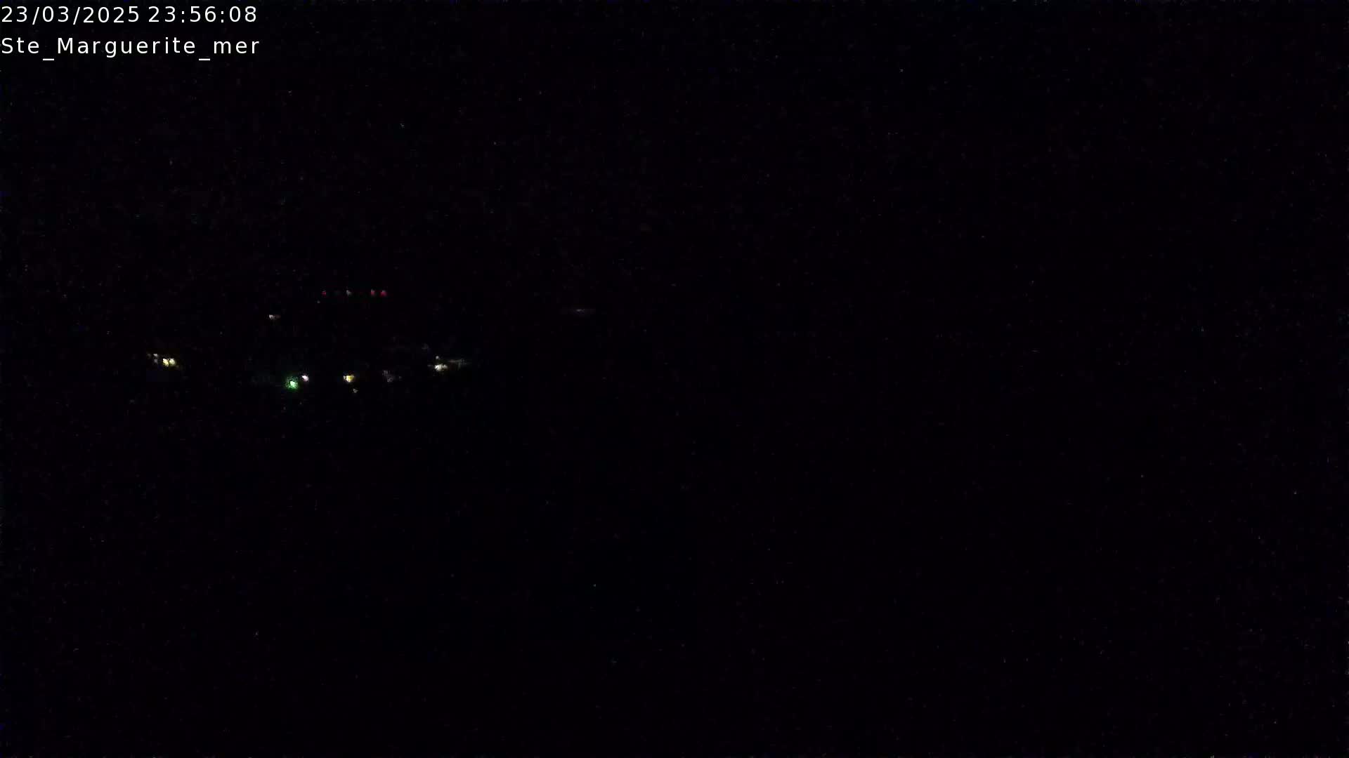 A nighttime long shot shows a few small, distant lights in the darkness.
