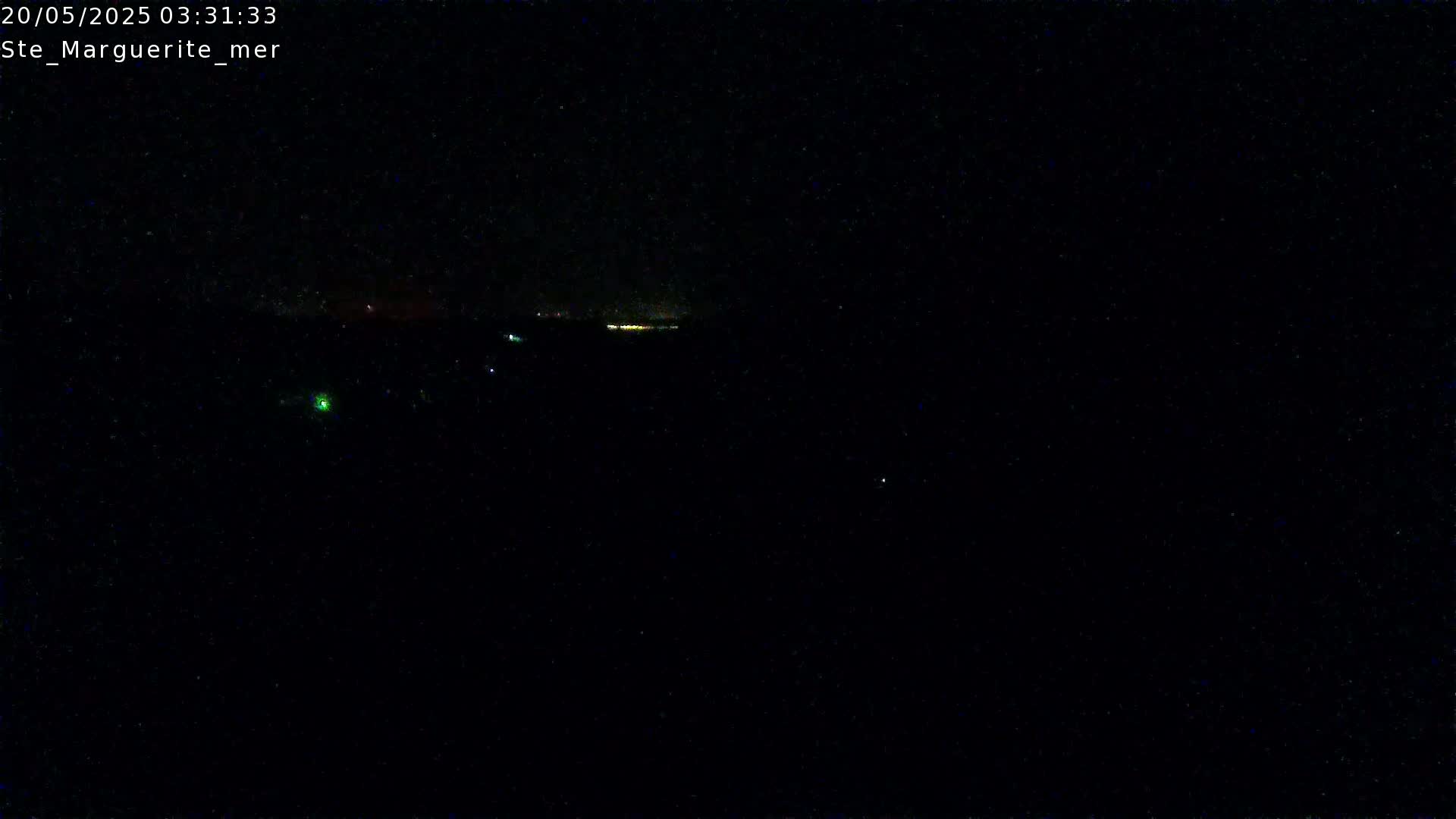 A nighttime, dark scene shows a distant line of lights on the horizon.