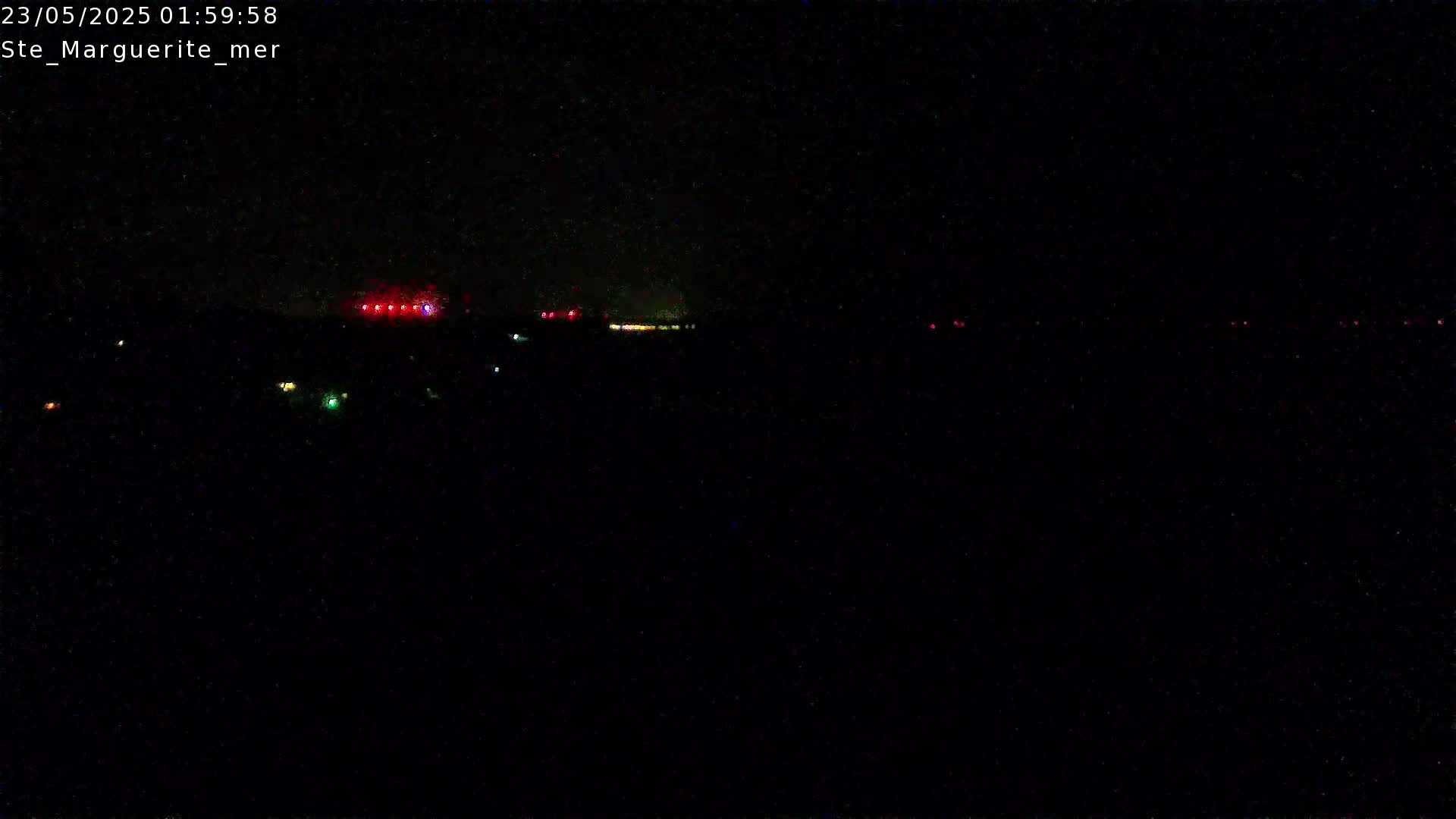 A nighttime, long-distance view shows a line of faint, multicolored lights in the distance.
