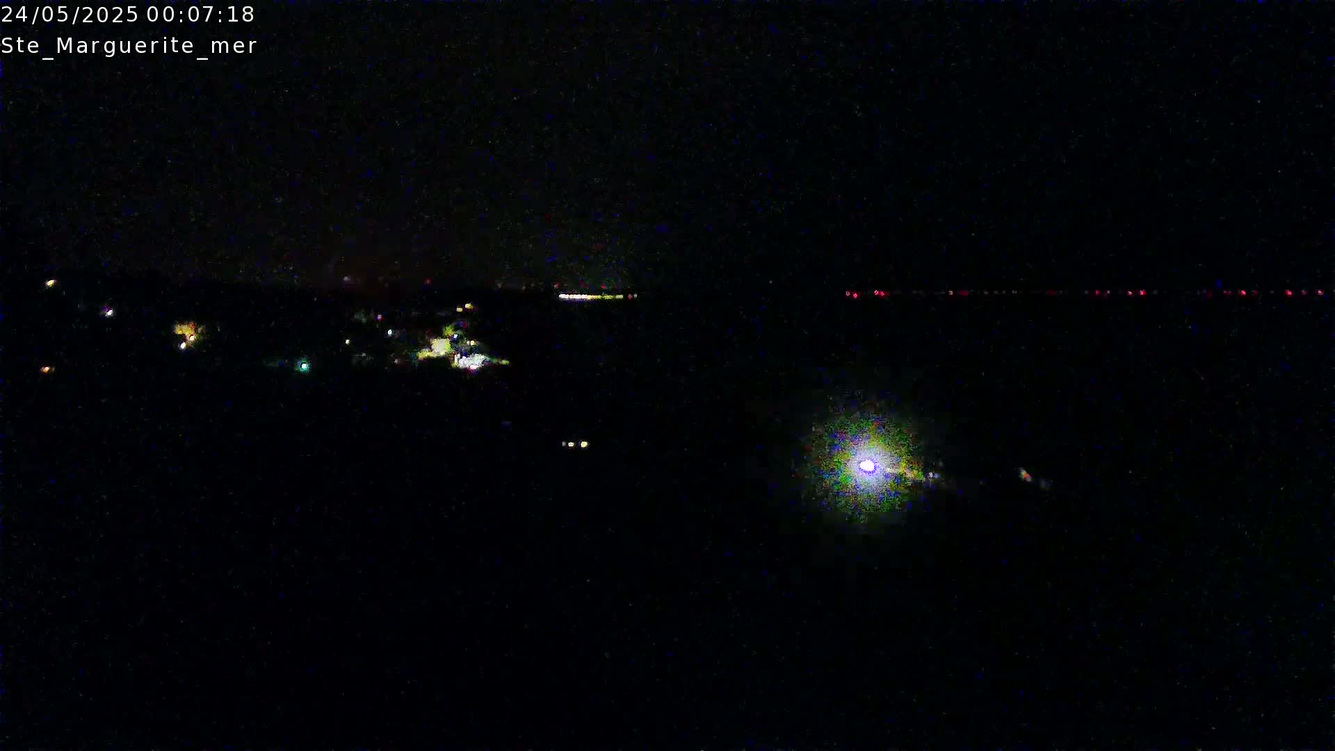 A nighttime long shot shows a dark landscape with scattered lights in the distance and a bright light source in the lower-middle.