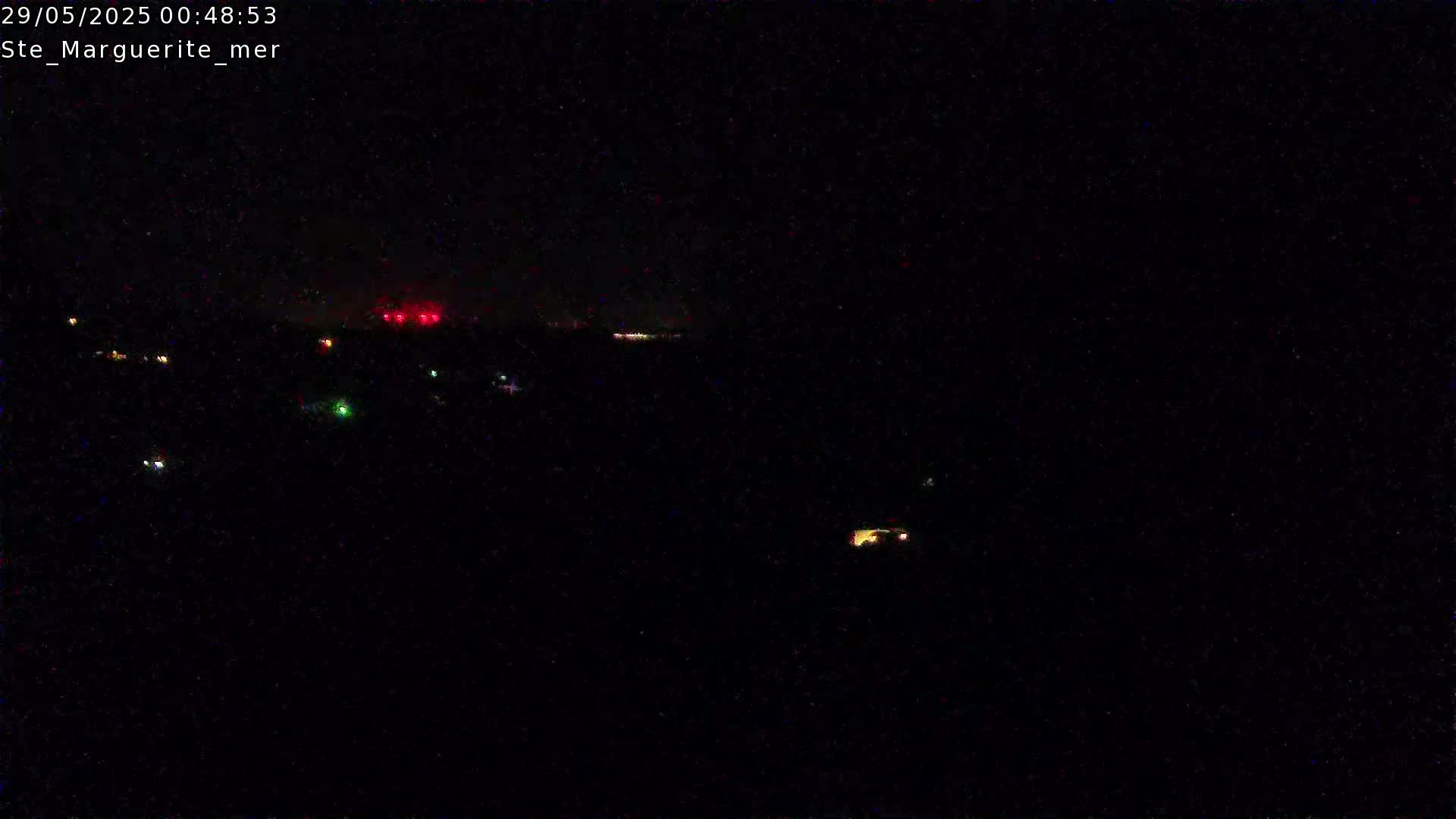 A nighttime, dark view shows a few scattered lights in the distance, possibly from houses or vehicles.