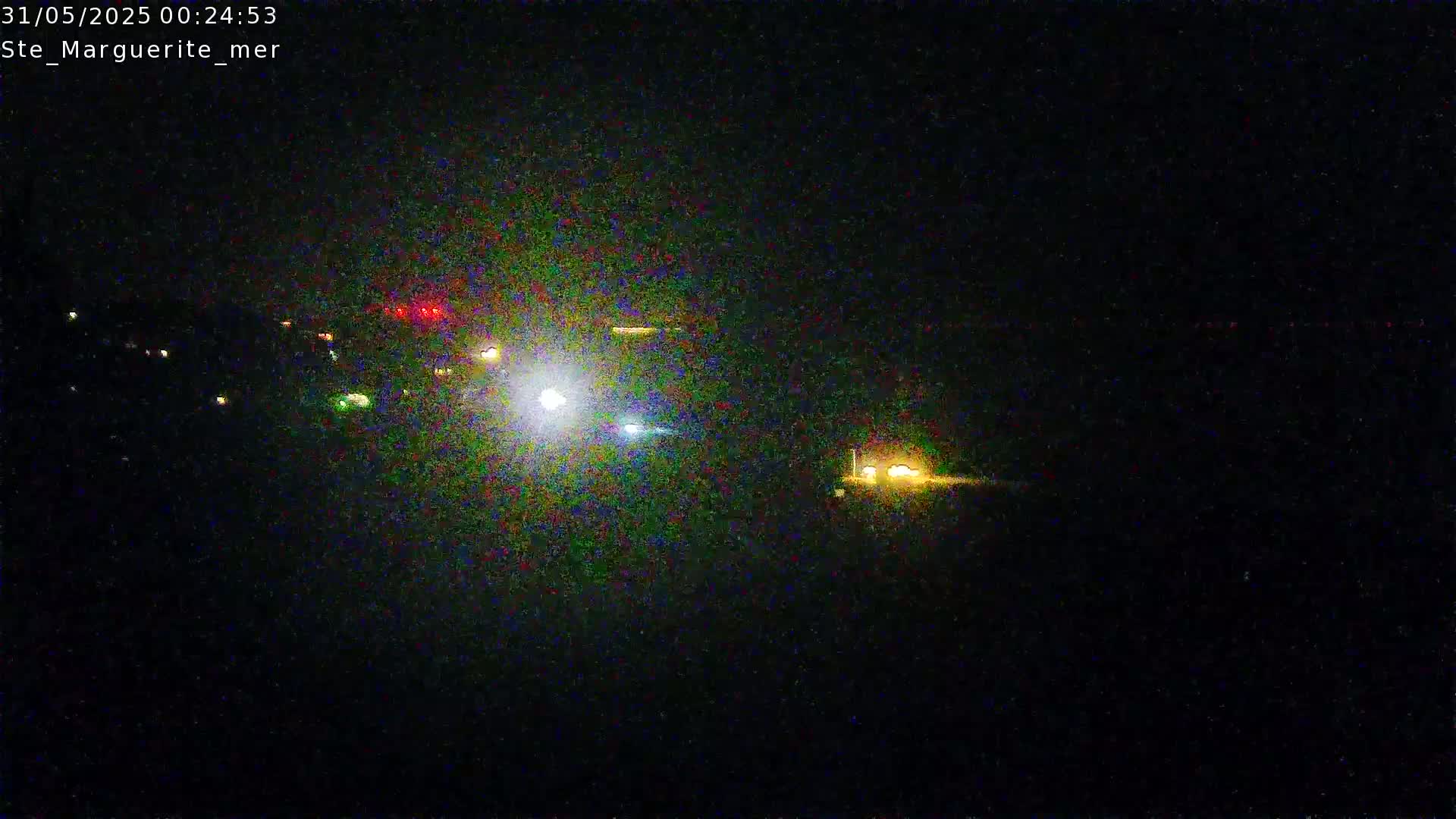 A nighttime, long-range view shows a collection of distant lights, possibly from vehicles or buildings, under a dark sky.