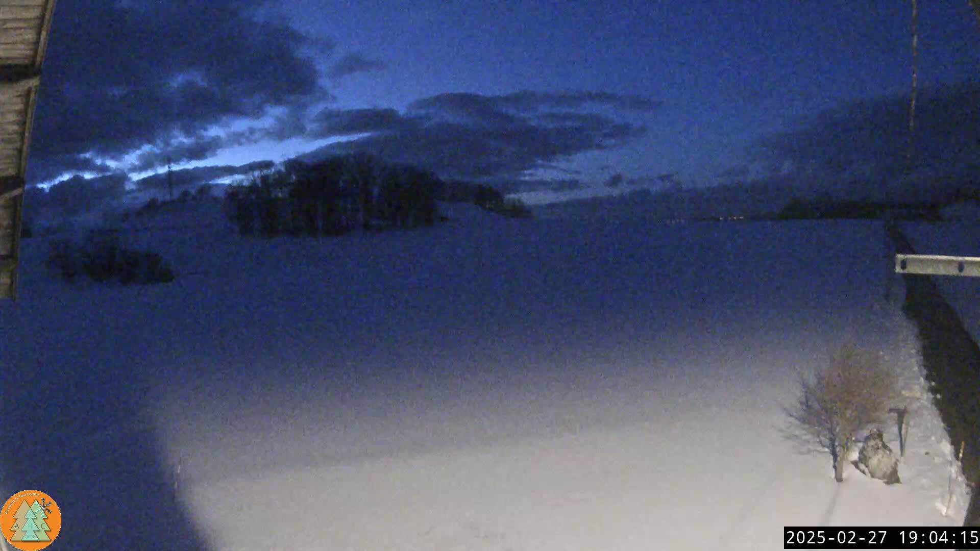 A snow-covered landscape stretches out under a dark, cloudy twilight sky.