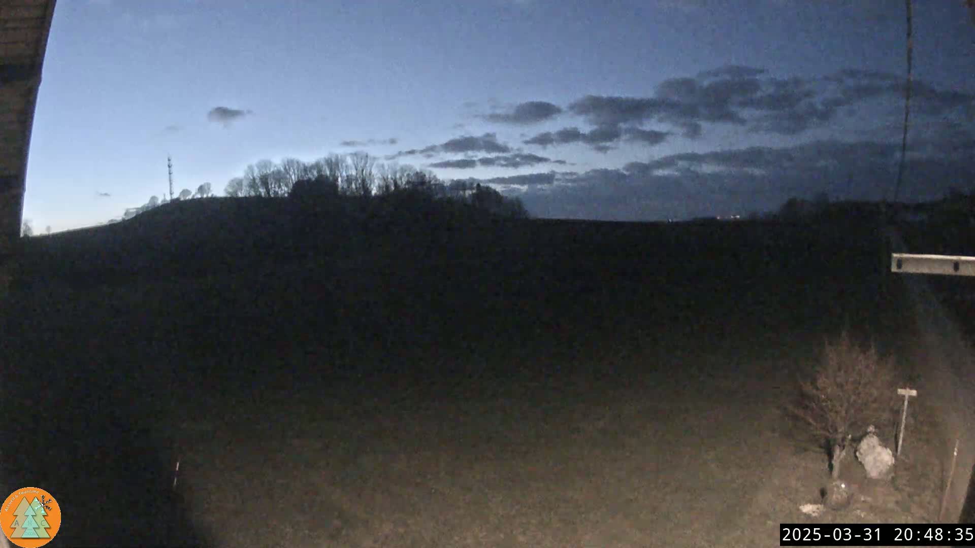 A dark, mostly flat landscape under a twilight sky with some clouds is visible from a slightly elevated vantage point.