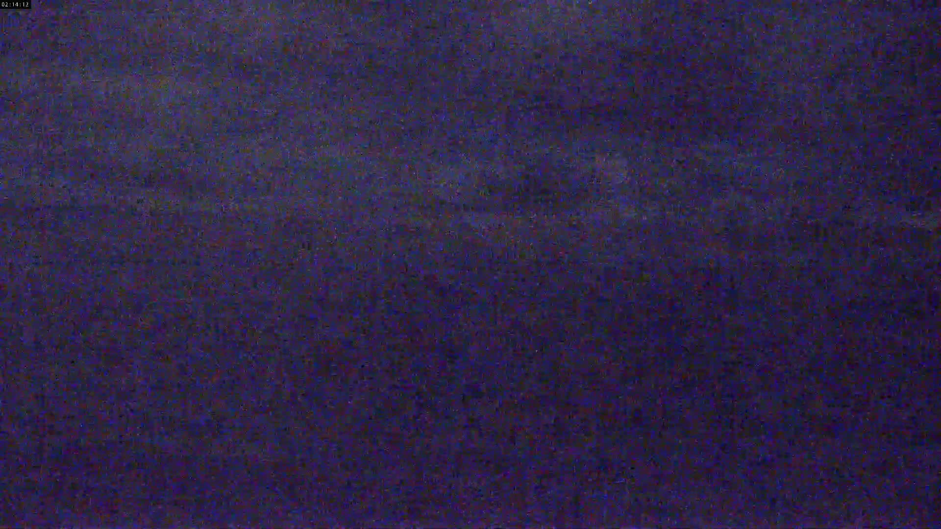 A dark, blurry image shows a mostly uniform expanse of dark blue-purple, possibly depicting a nighttime landscape under a cloudy sky.