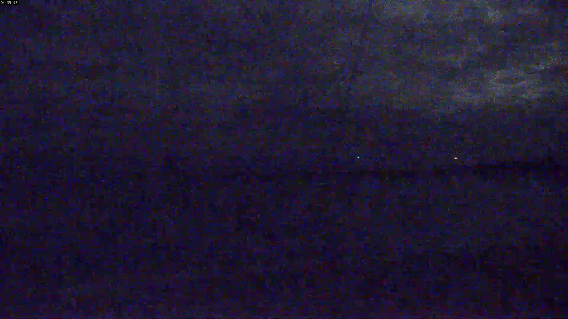 A dark, nighttime scene shows a body of water under a cloudy sky.