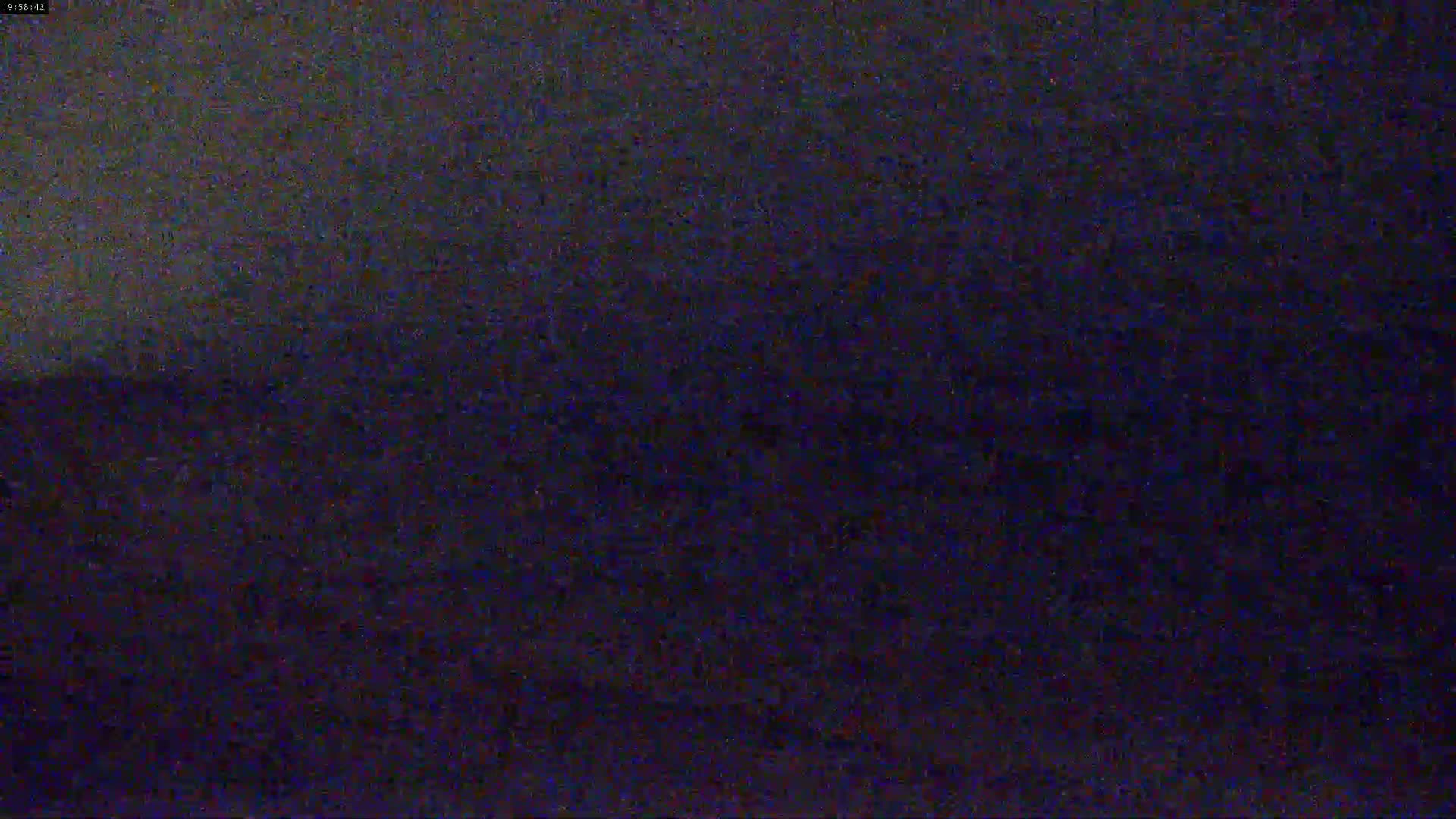 A dark, grainy image shows a mostly featureless, dark-colored landscape under a dark sky.