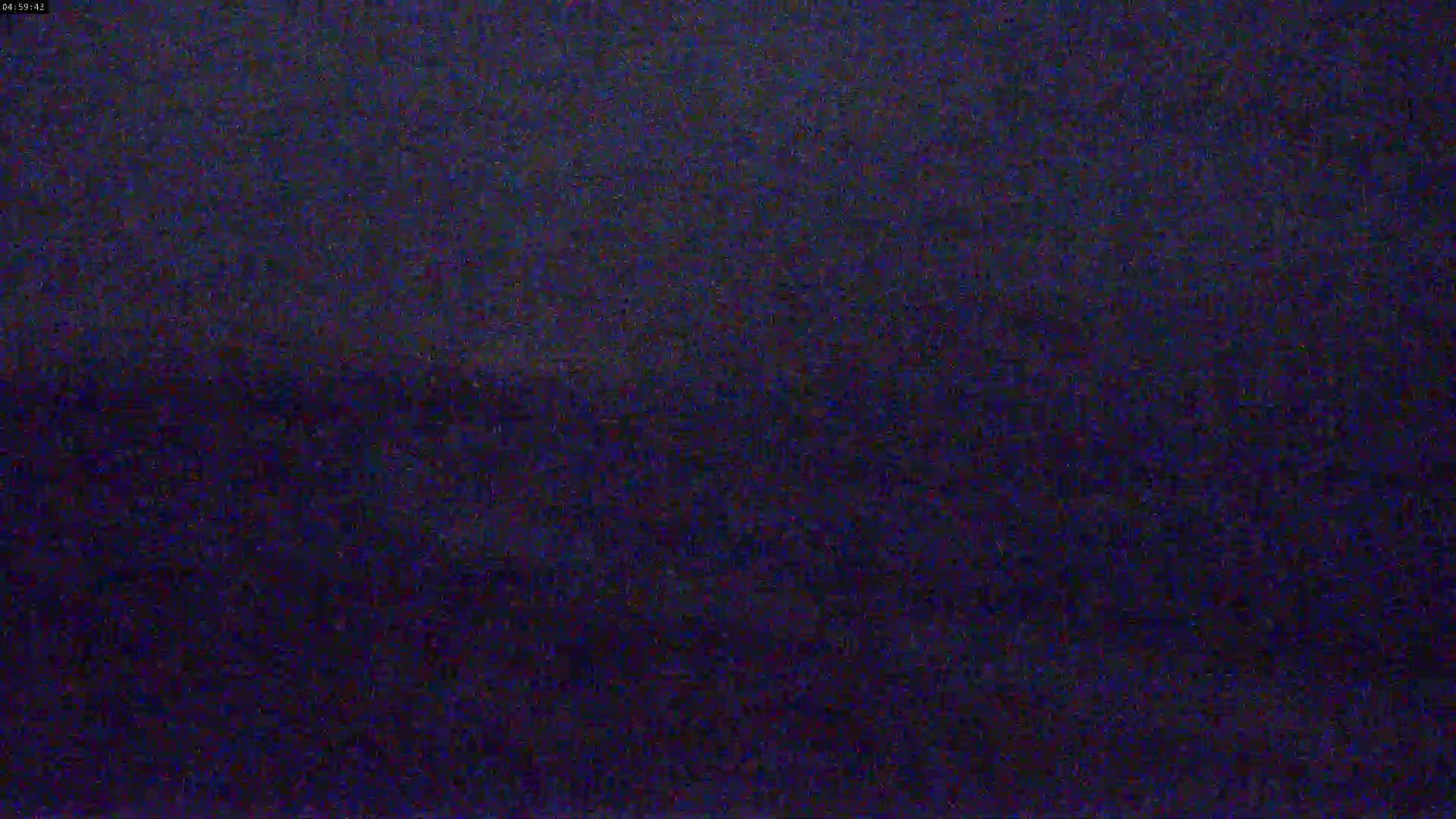 A dark, grainy image shows a mostly uniform dark blue-purple color with subtle variations in shading.