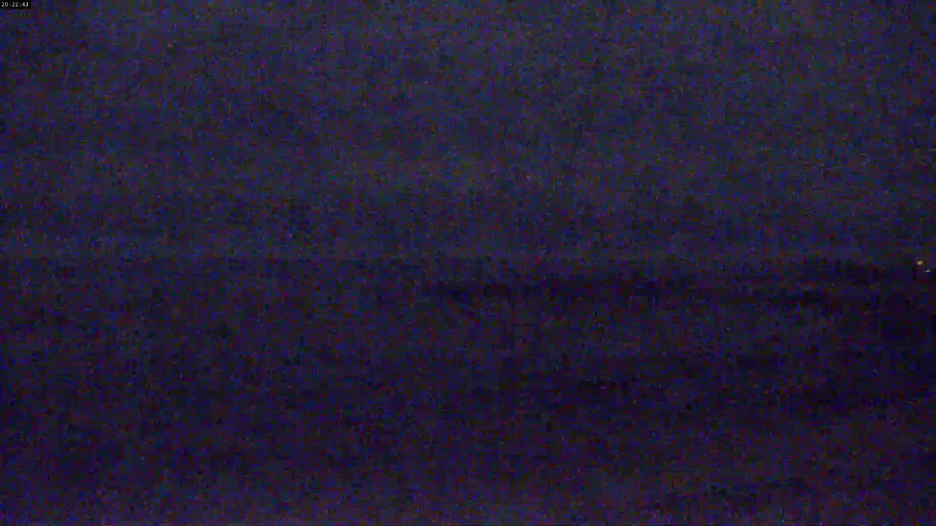 A dark, blurry image shows a nighttime scene of what appears to be a body of water with a faint horizon line.