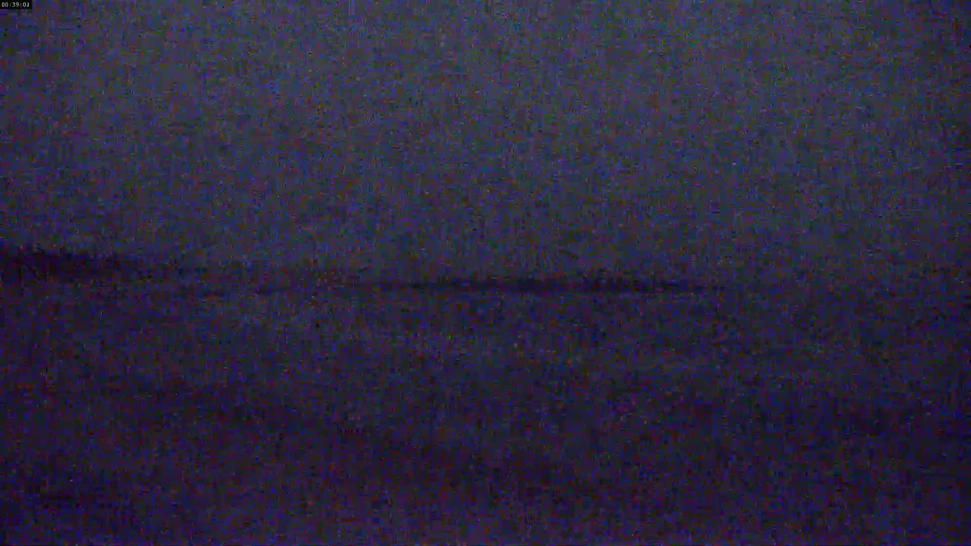 A dark, grainy image shows a mostly featureless expanse of dark water under a dark sky.