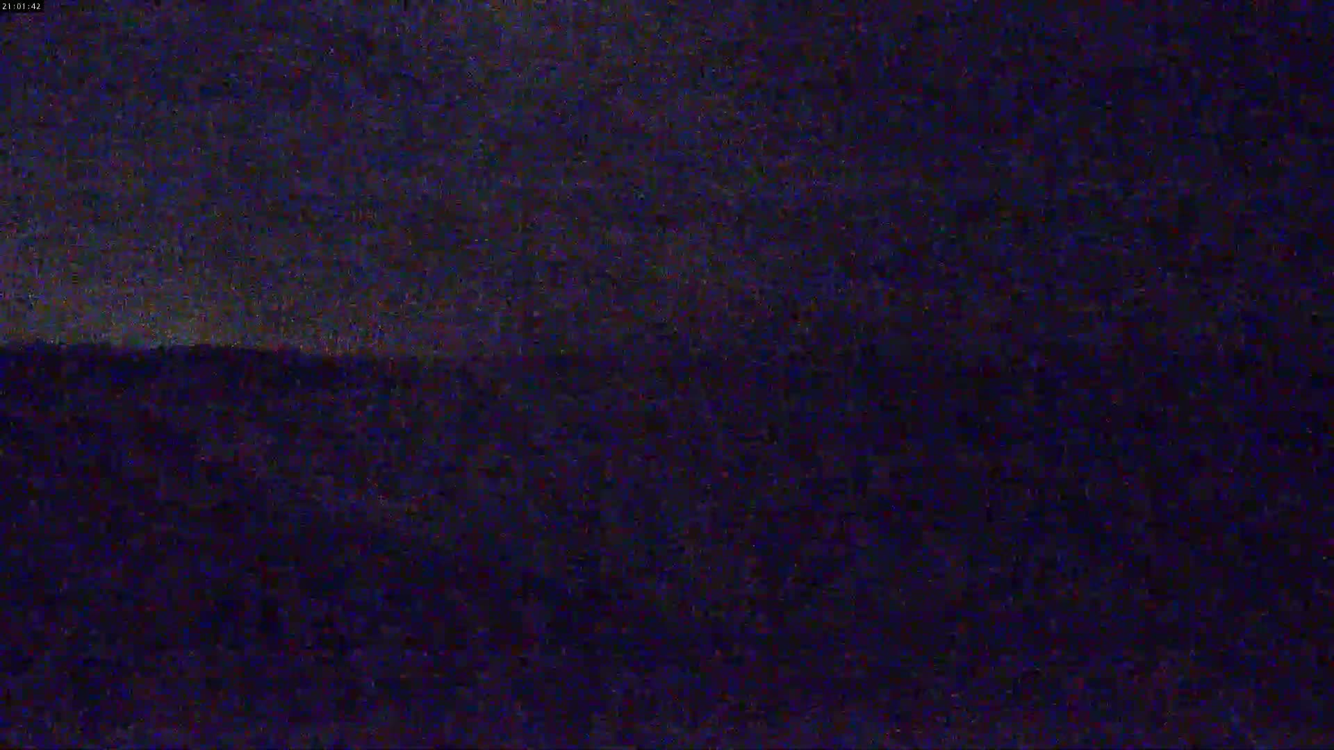 A dark, nighttime landscape is visible under a mostly cloudy sky.