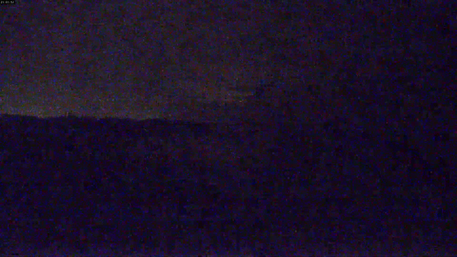 A dark, nighttime landscape is visible under a mostly clear, dark sky.