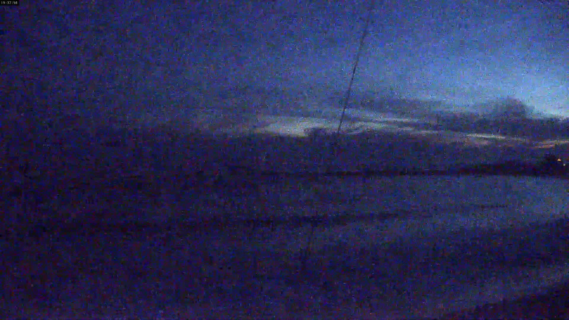 A dark, nighttime scene shows a flat expanse of land under a mostly cloudy sky.