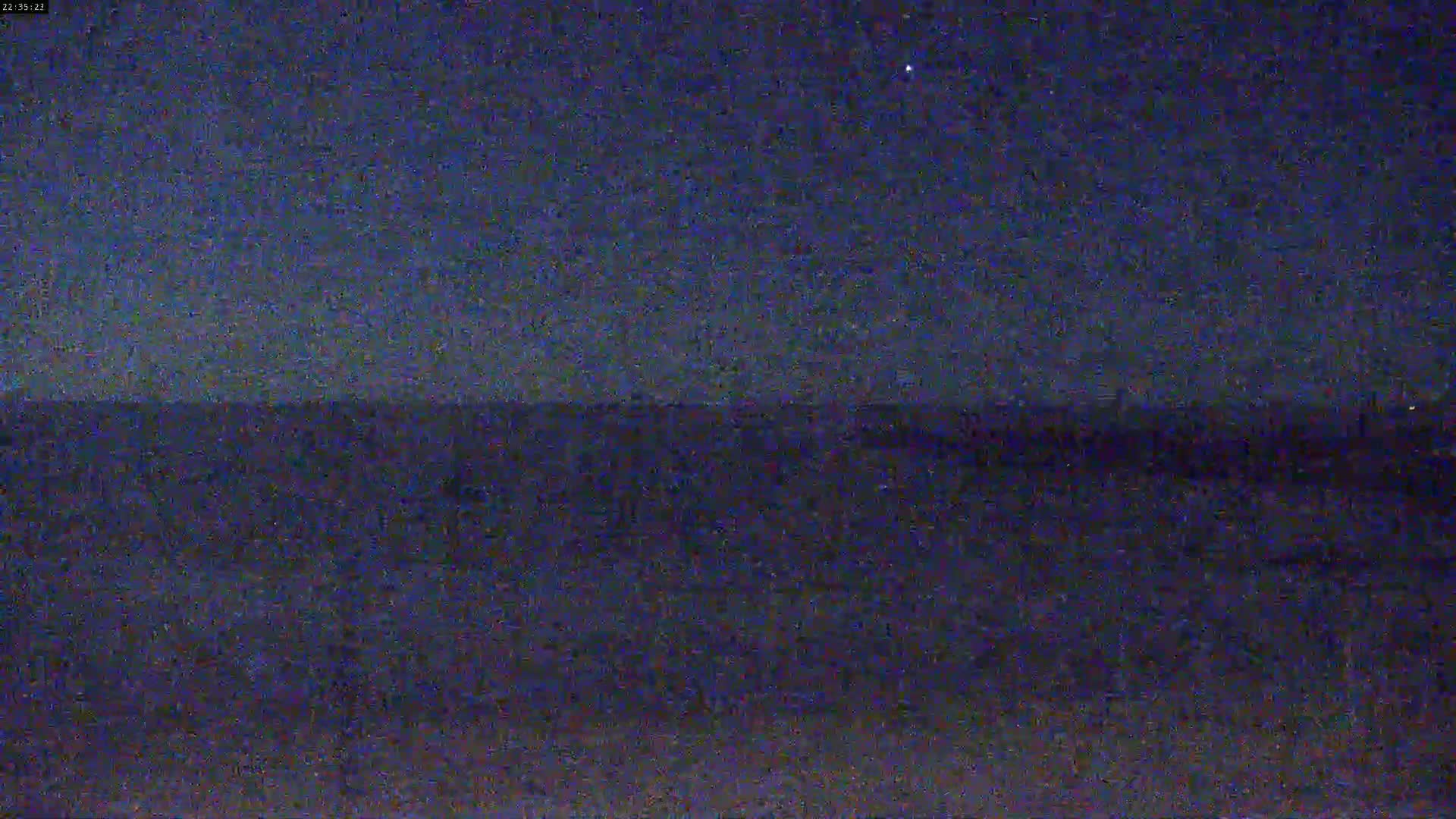 A dark, nighttime view of a flat, dark landscape under a clear, starry sky.